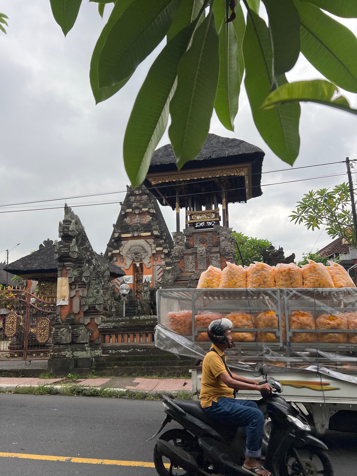 Artisan works metal craft amid bustling Ubud street scene
