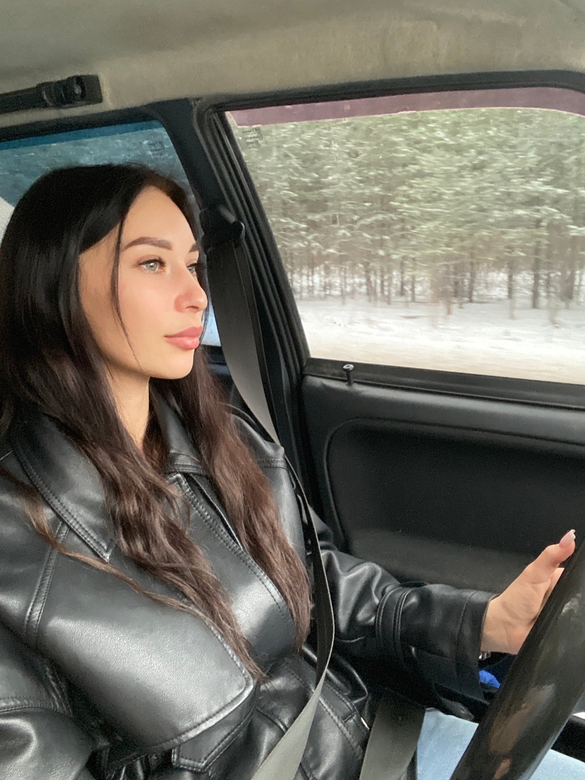 Woman observes winter landscape from car in Chaikovsky, Russia