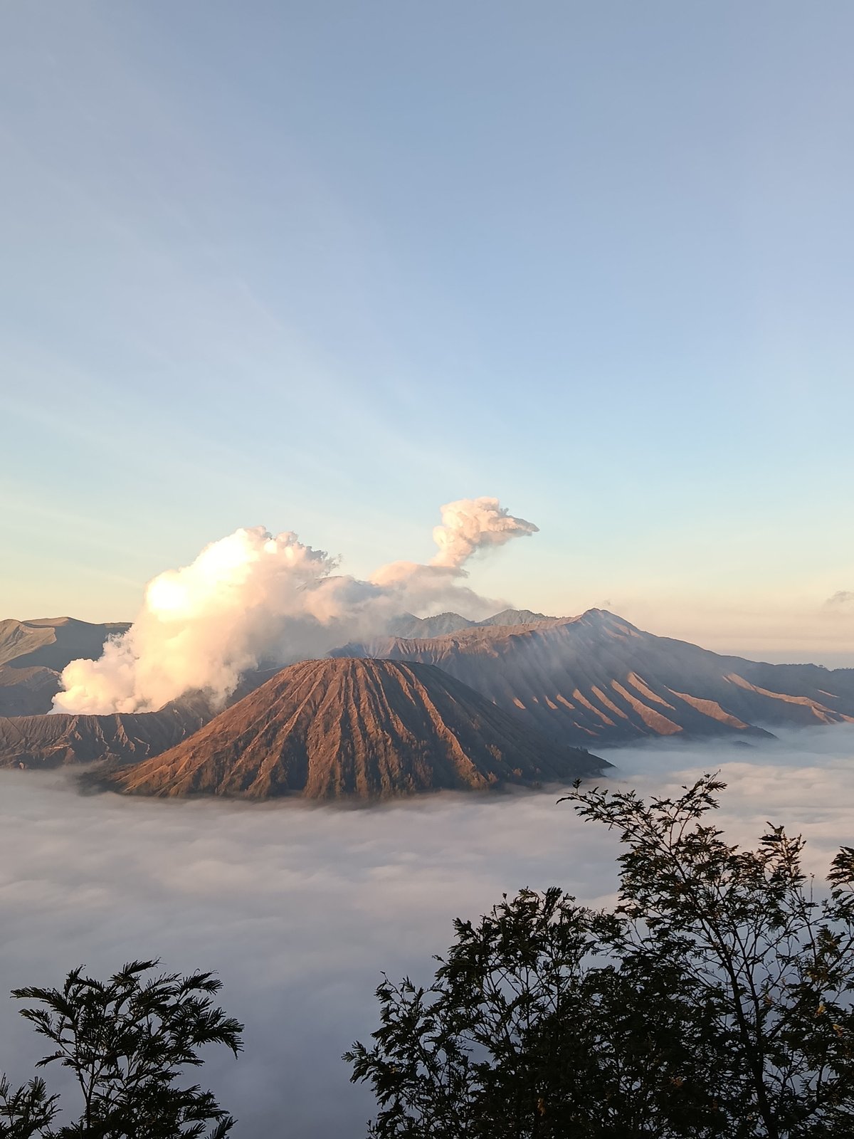 Mount Bromo erupting at sunrise, crowds gathering at viewpoints