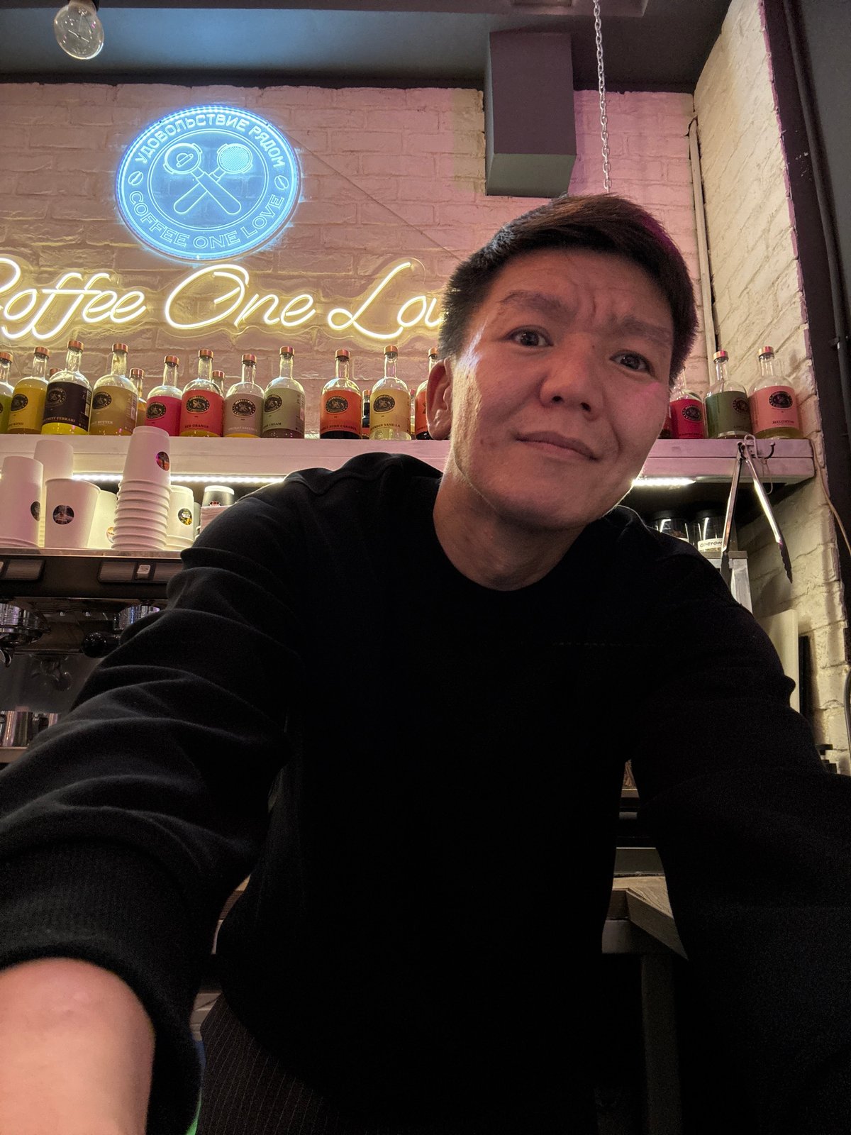 Inside a neon-lit Moscow coffee shop, mid-afternoon.