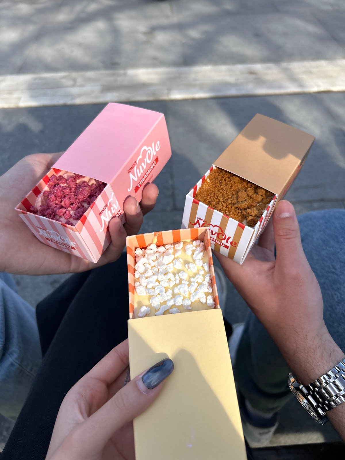Three people enjoy tiramisu boxes near Sofia's NDK building