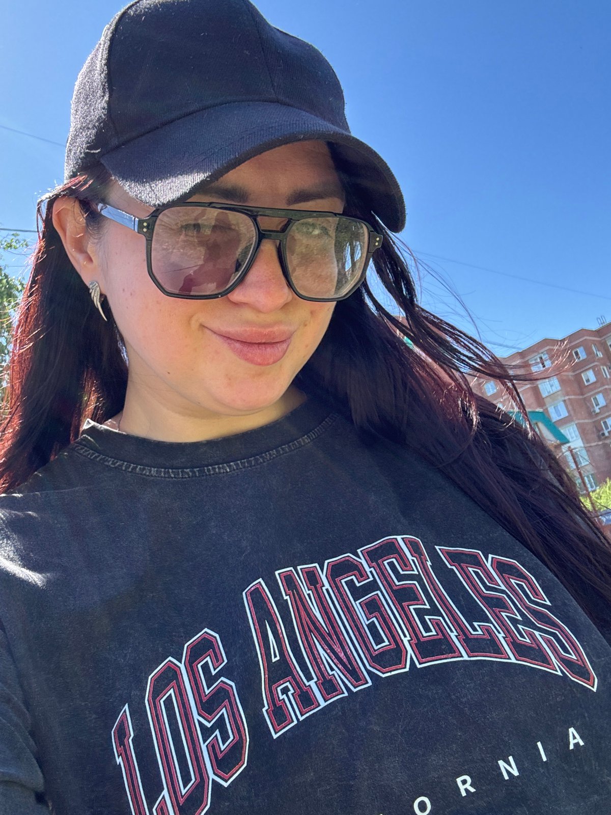 Woman in LA shirt takes selfie near apartments