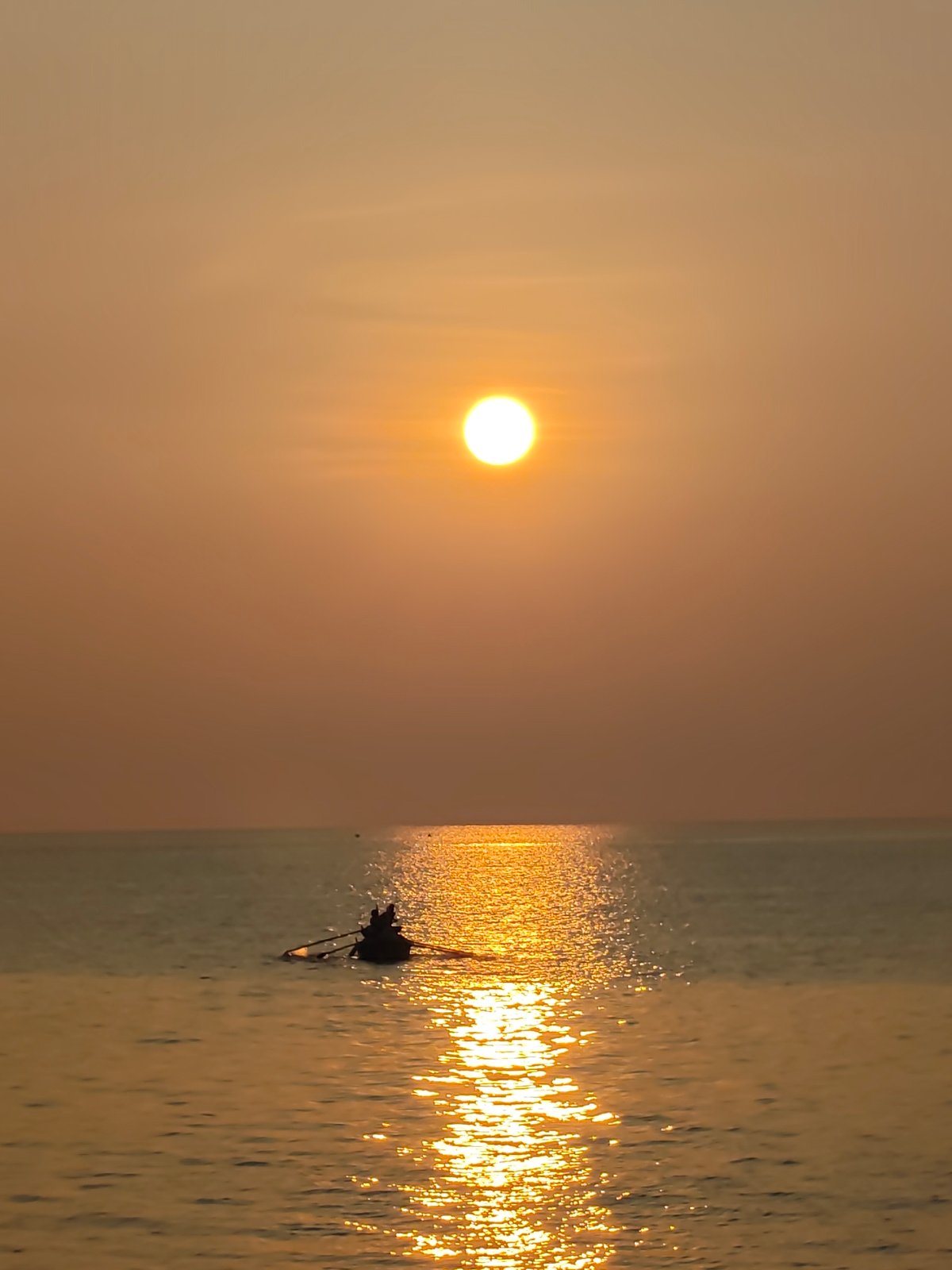 Golden sunset documented along Lhokseumawe coast with boats, beachgoer