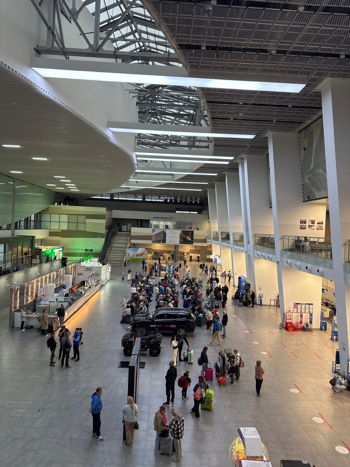 Russian airport terminal shows normal passenger activity, multilingual signage