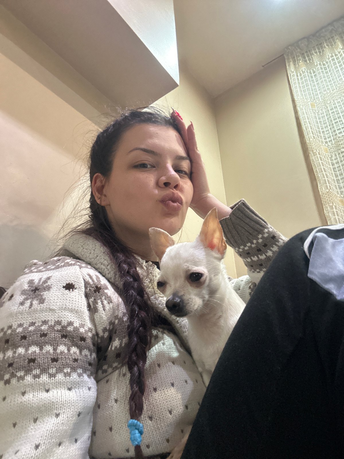 Person poses with small white dog in affectionate moment