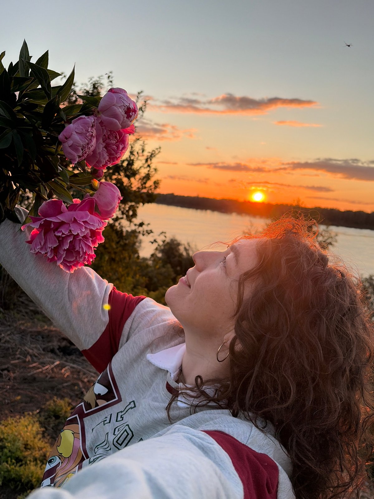 Woman poses with pink peonies during sunset in Ольховка