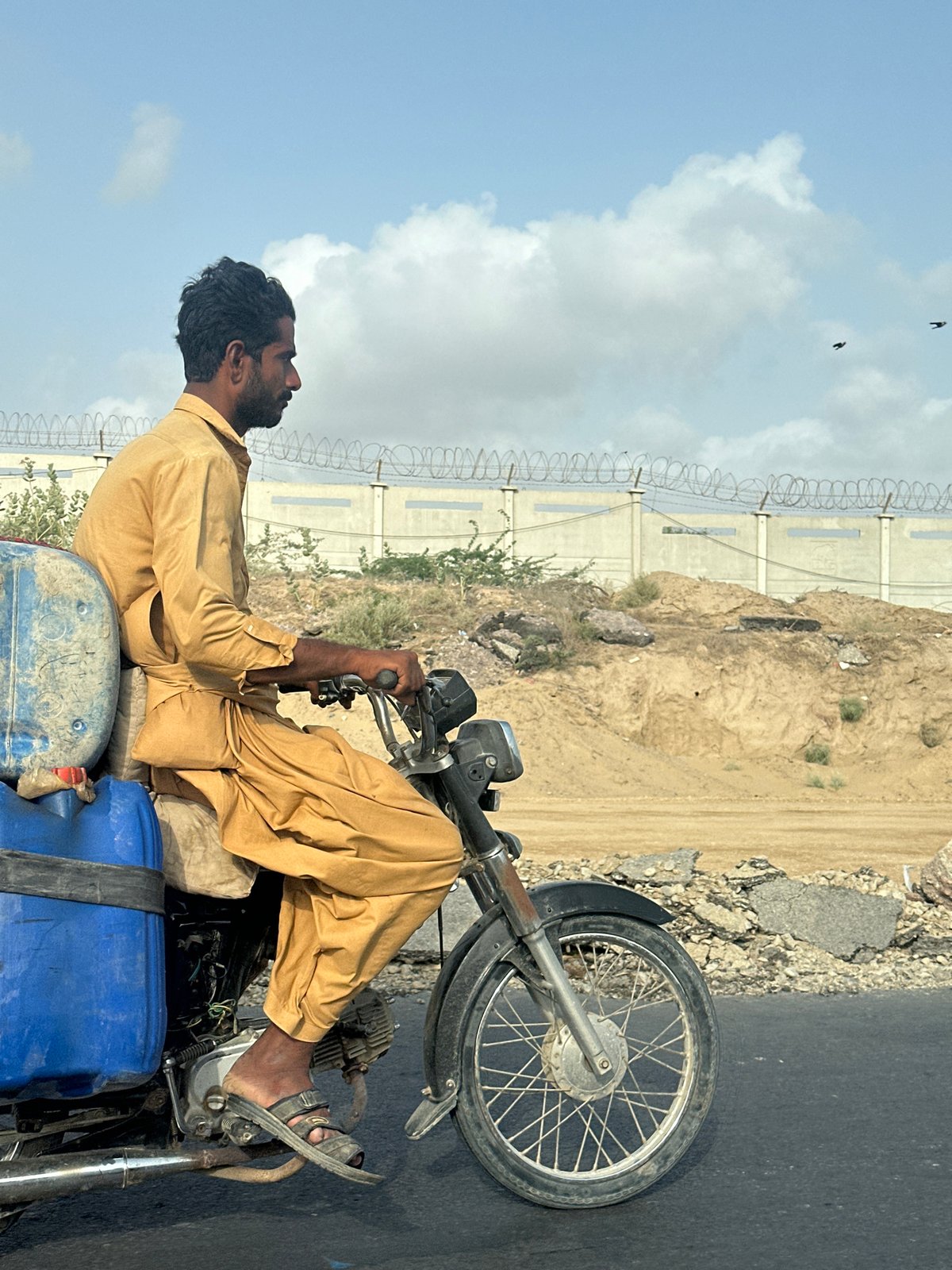 Motorcycle hauling large plastic barrels through Winder, Pakistan