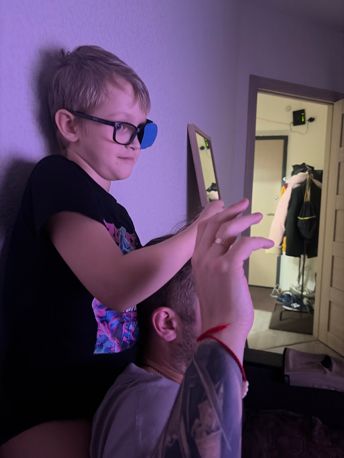 Child with eye patch comforted by adult indoors