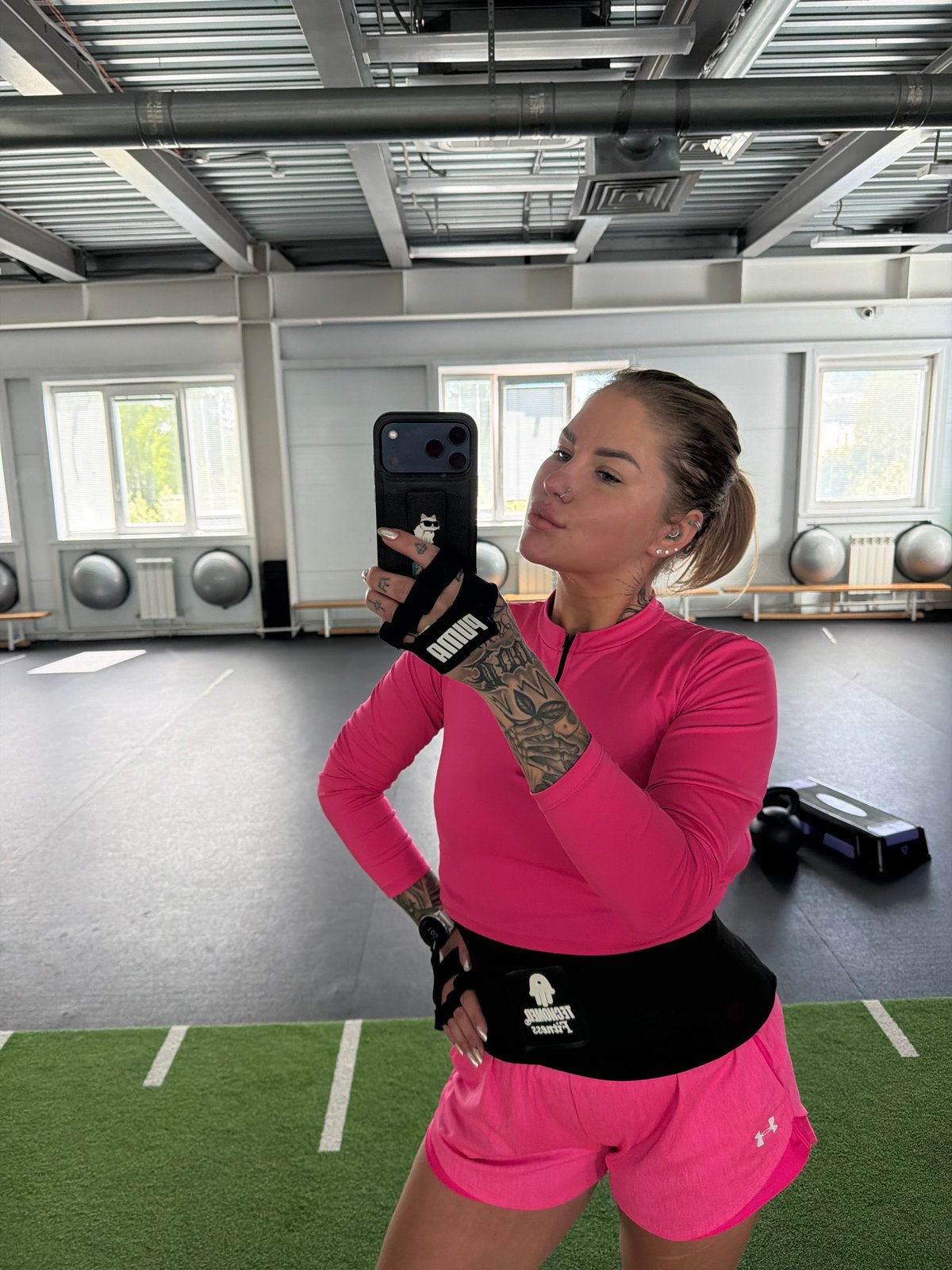 Woman takes gym selfie in pink workout gear in Mayma