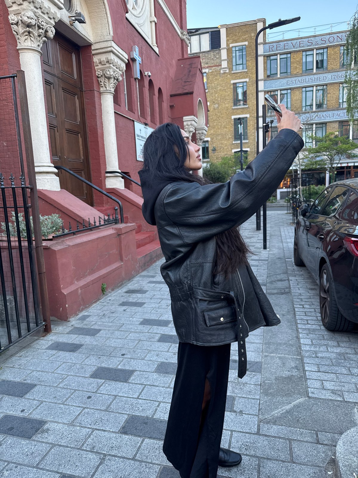 Woman photographs London street scene near graffiti bridge artwork