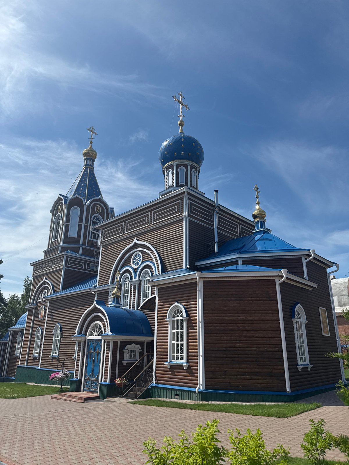 Log Orthodox church and garden flowers in Tashla, Russia