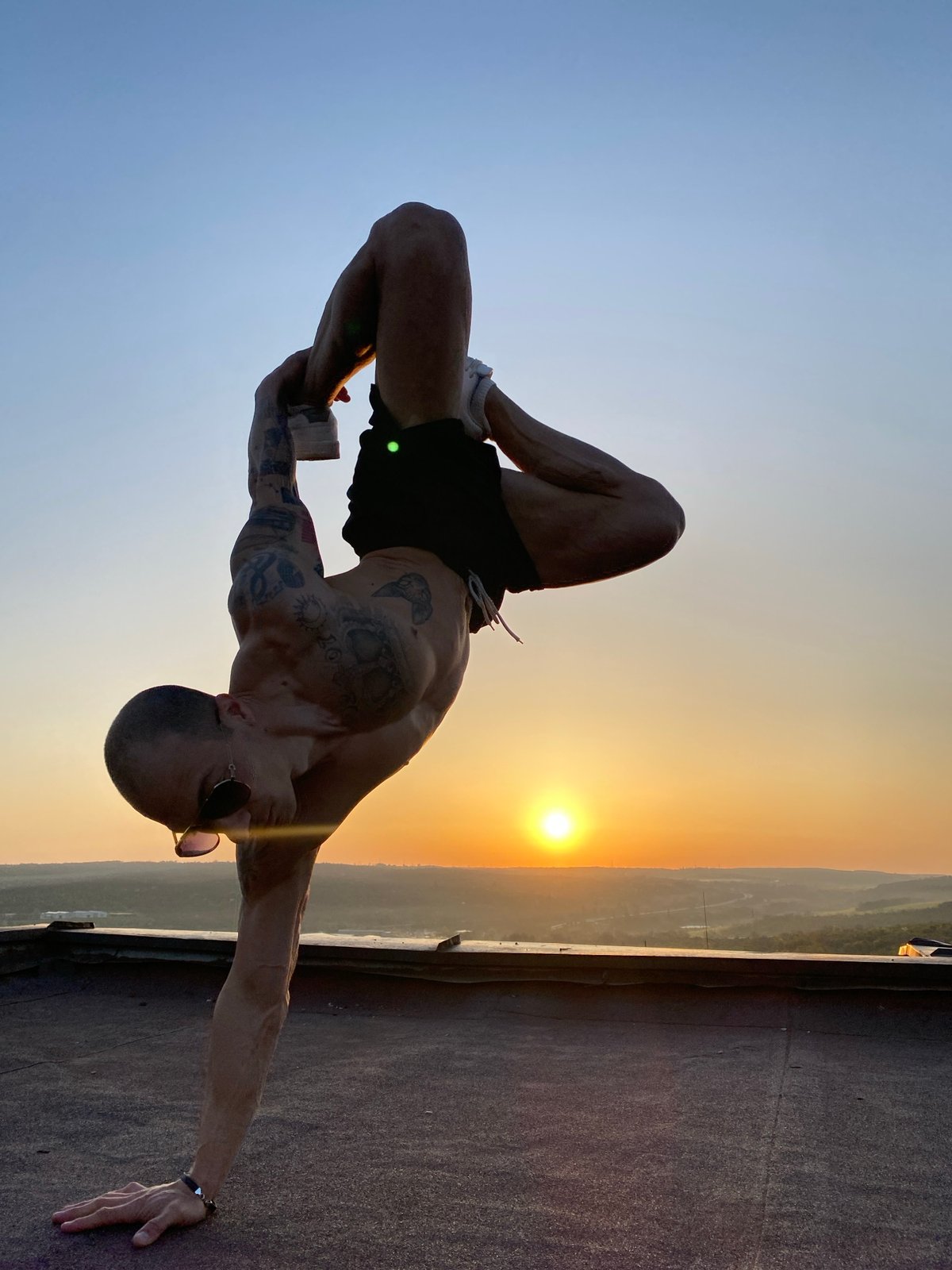 Tattooed man performs flexible pose at sunset in Pleven