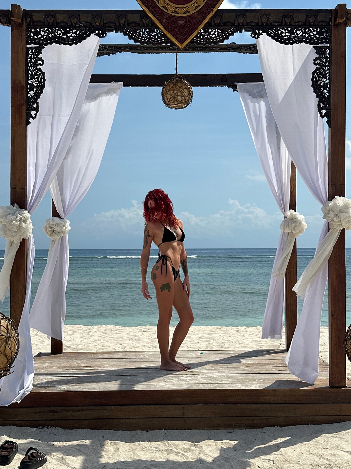 Woman poses on wooden deck overlooking ocean in Indonesia