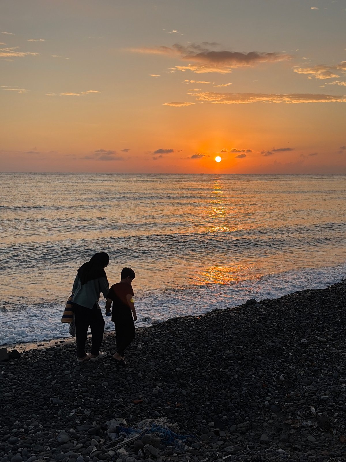 Sunset over the ocean from Abang's pebble beach