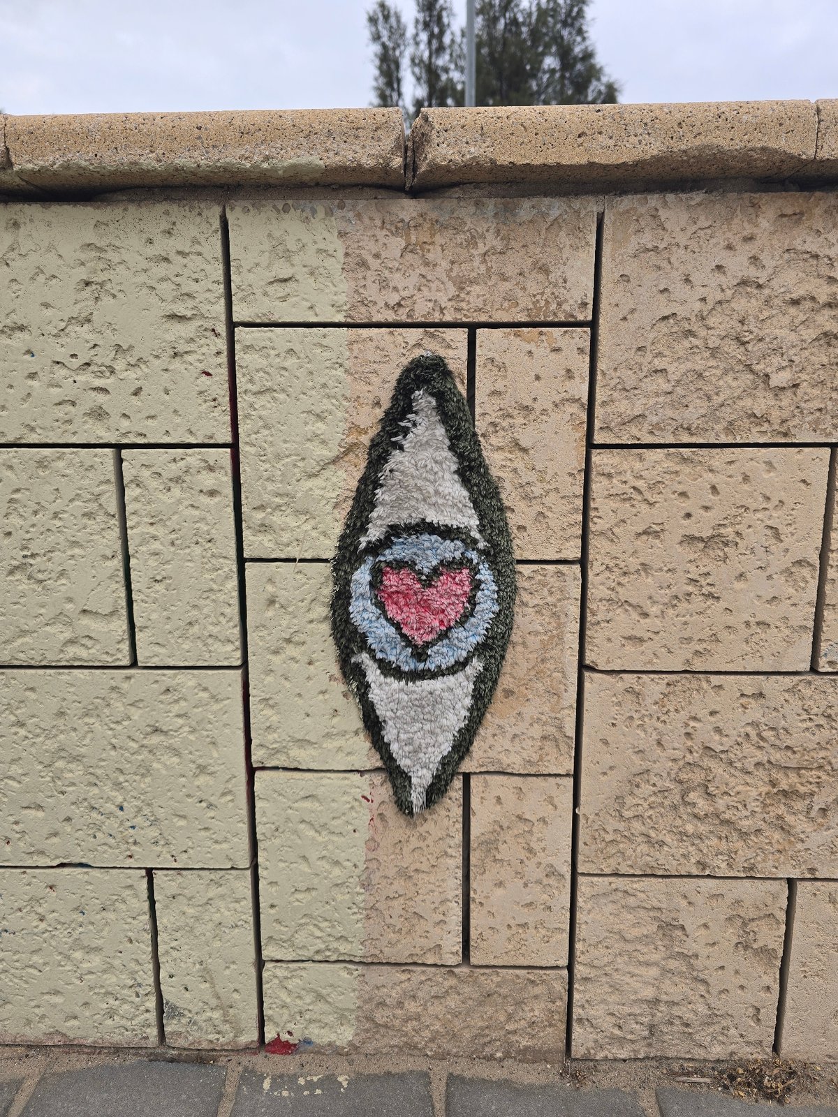 Eye-shaped yarn bombing with heart center spotted on Tel Aviv wall