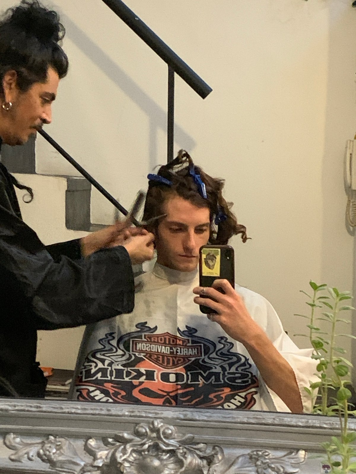 Mirror reflection captures two people, one holding scissors in Buenos Aires
