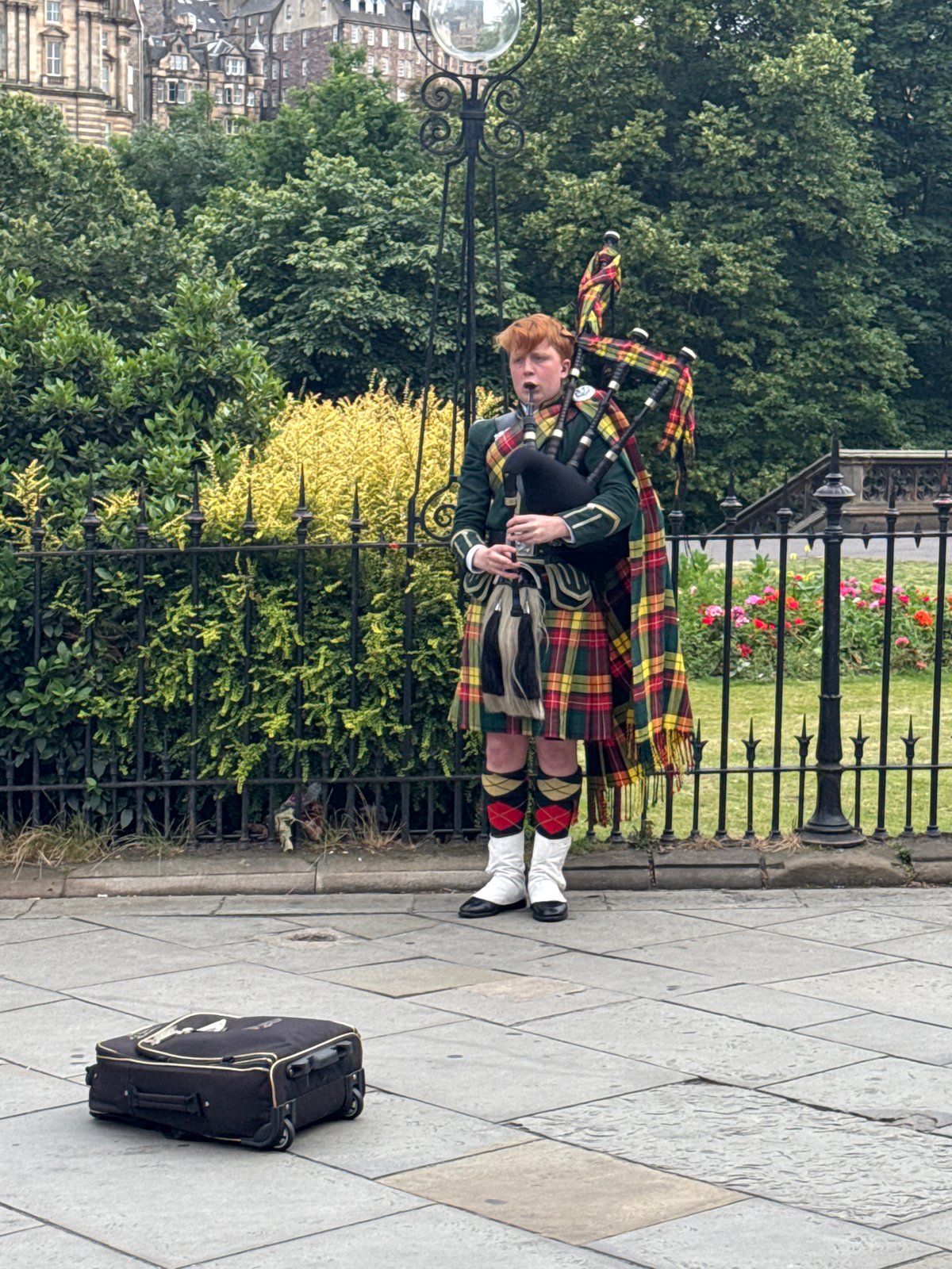 Scott Monument and street piping in Edinburgh on a cloudy afternoon