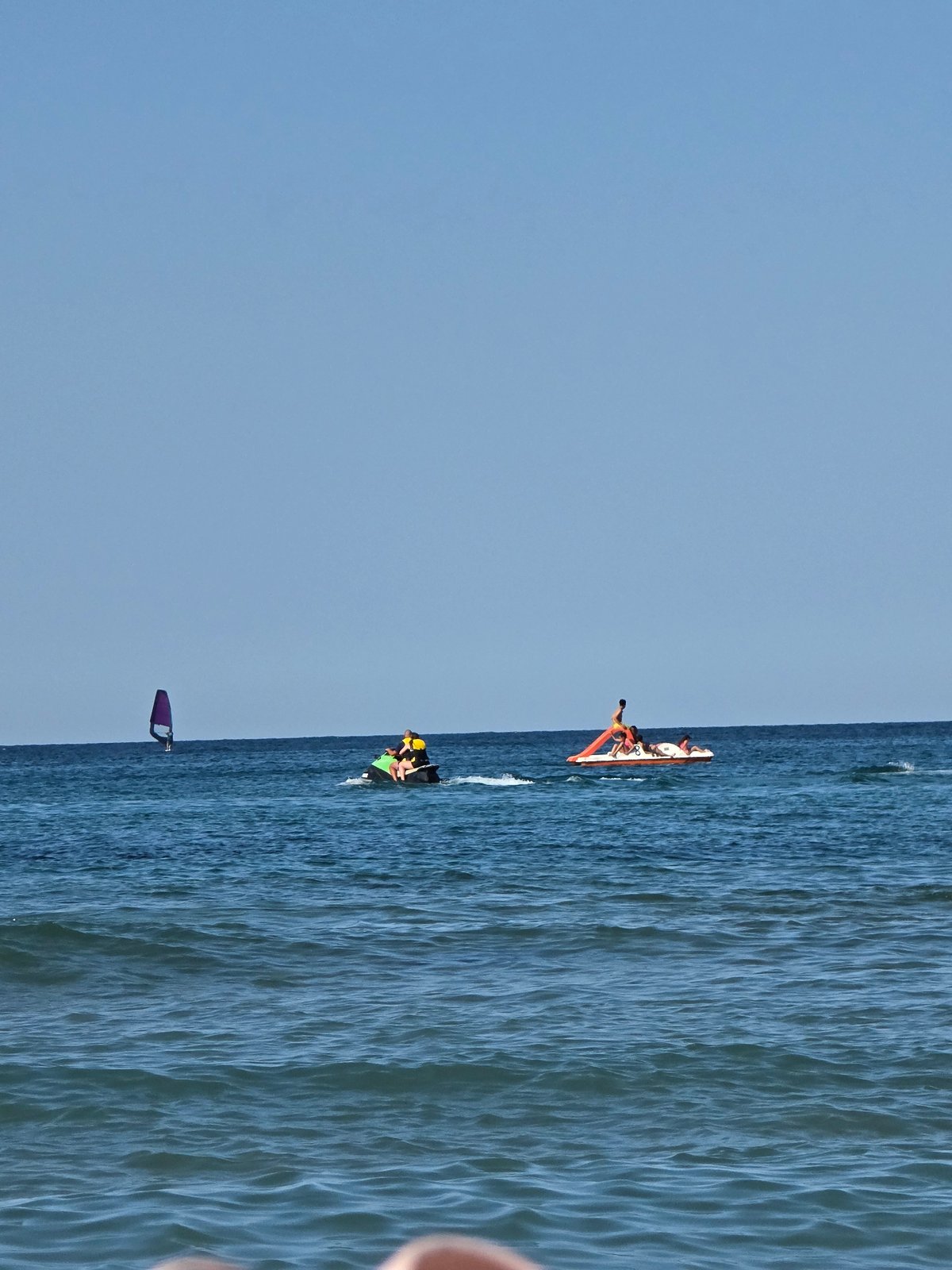 Busy ocean day: paddleboarding, swimming, and watersports in full swing