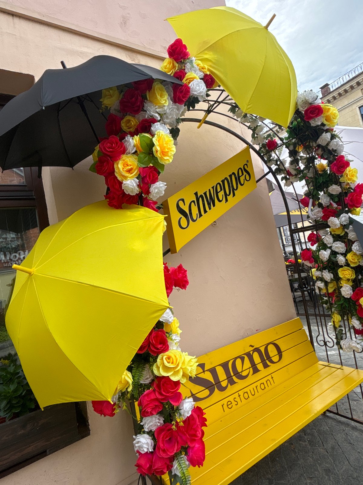 Decorated outdoor café frontage with branded furniture and floral archway