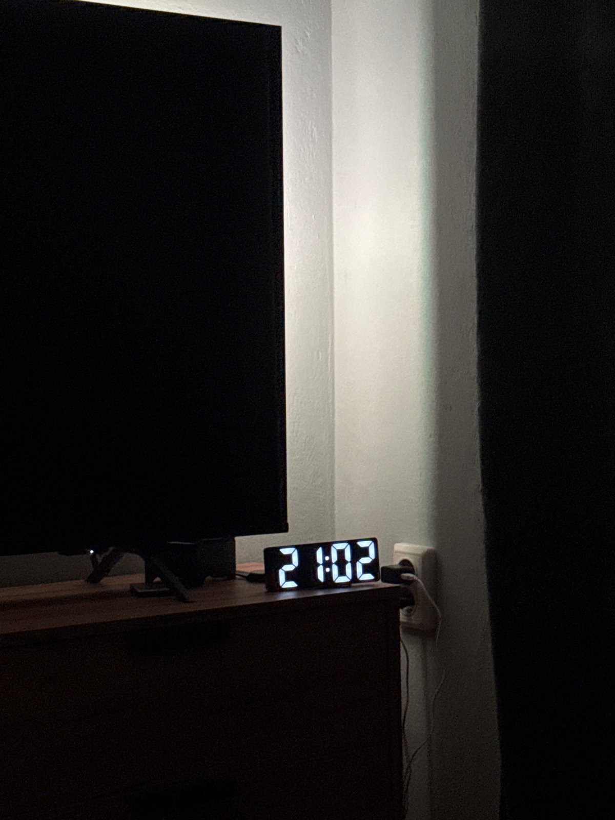 Digital clock shows 9:02 PM in dimly lit room