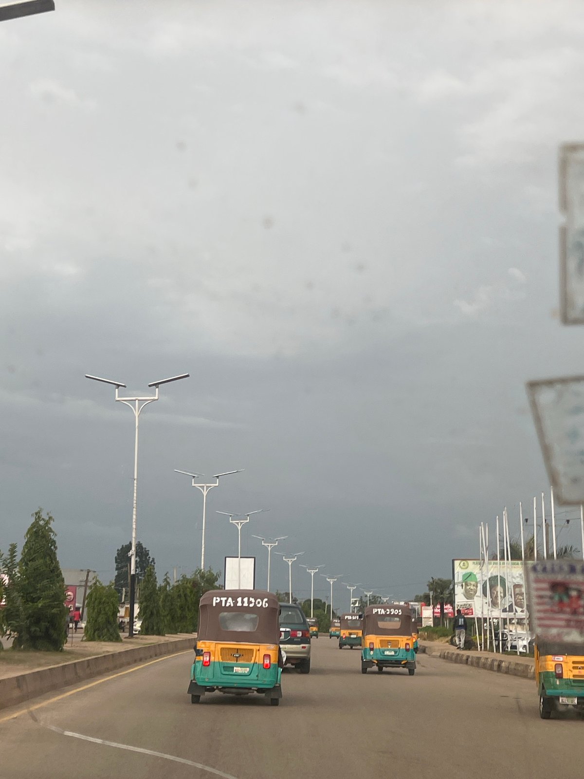 Street-level look at Jos roads, keke traffic, and infrastructure signage