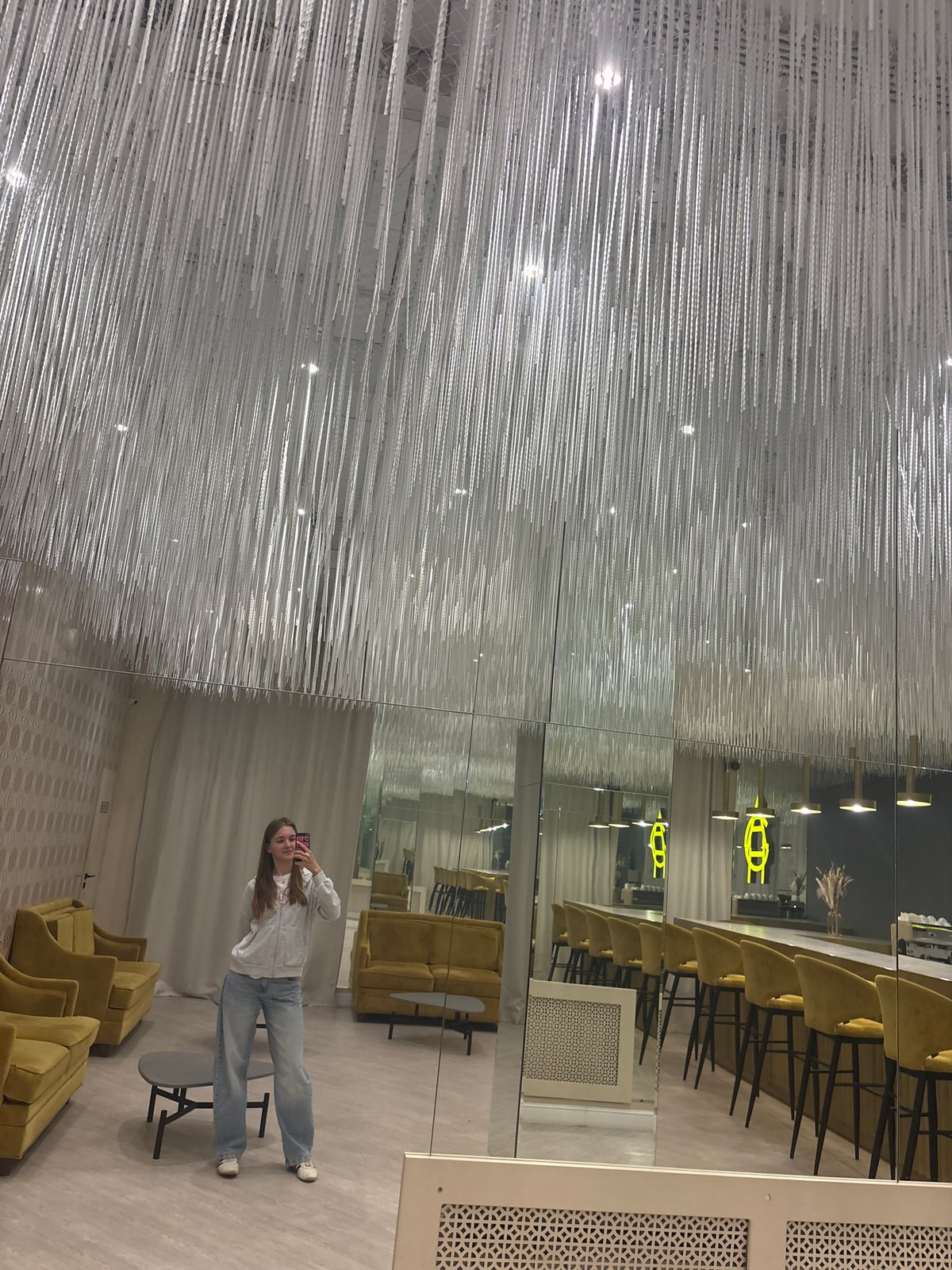 Woman takes mirror selfies in Perm showroom with artistic ceiling