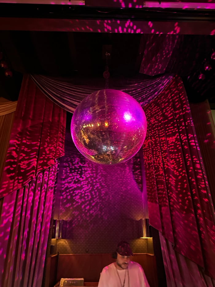 Disco ball casts pink light in dimly lit London venue