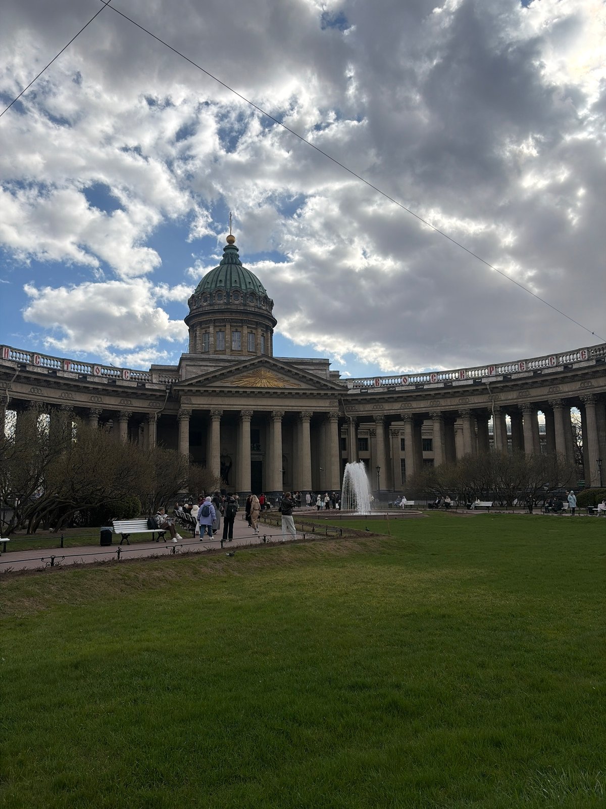 Tourists photograph Kazan Cathedral under cloudy skies in Saint Petersburg