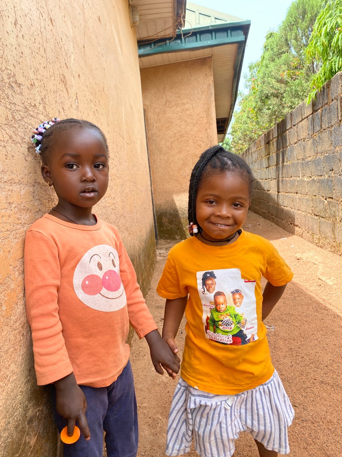 Two girls share fruit during morning play in Kuru, Nigeria