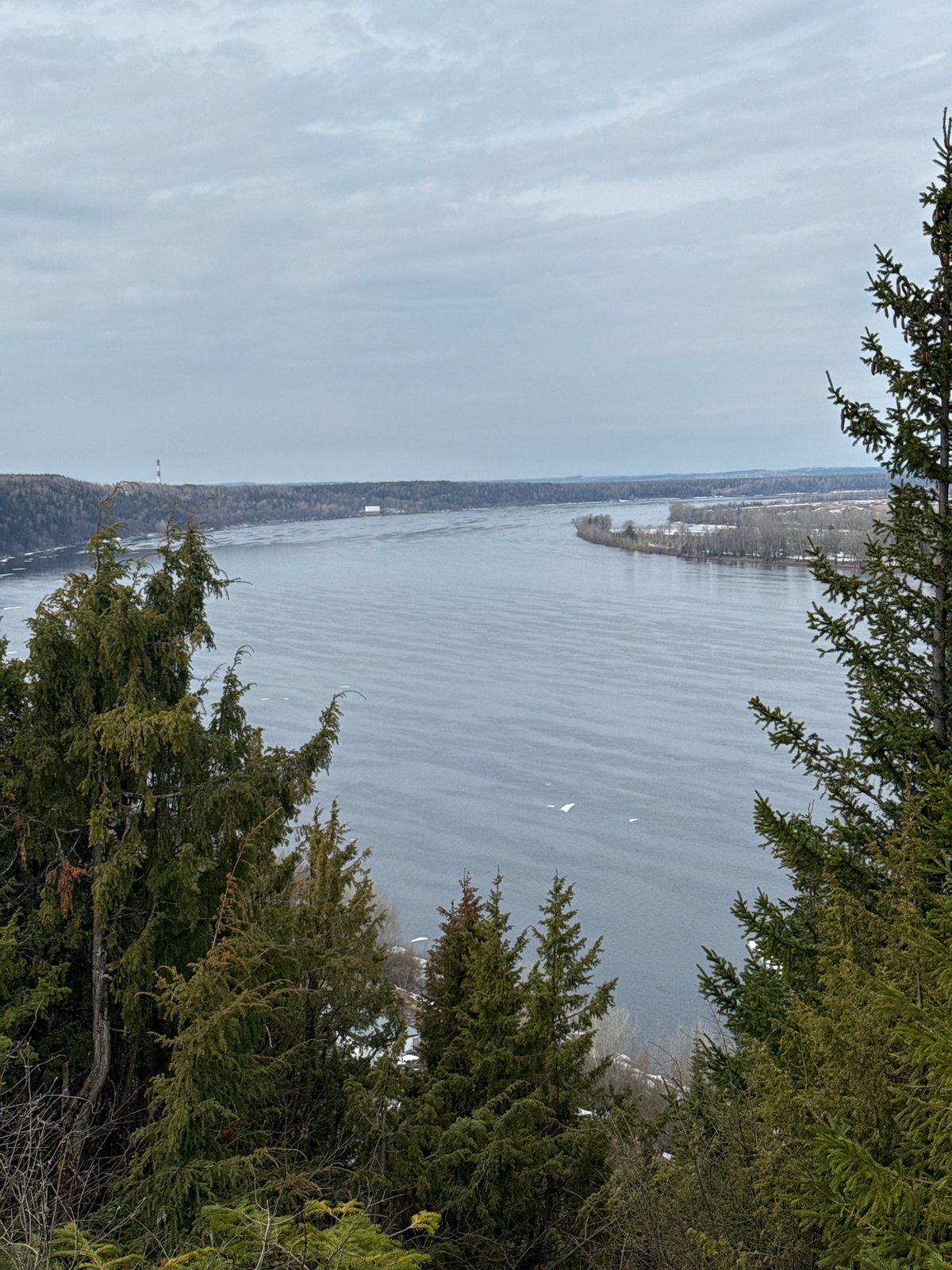 Elevated view captures water body with snow patches, evergreens