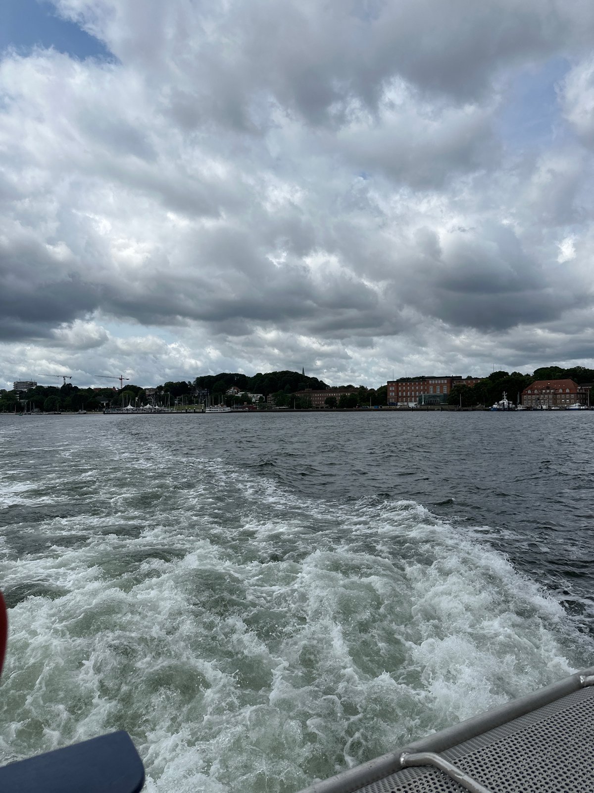 Out on Kiel Fjord, city skyline receding behind a moving boat