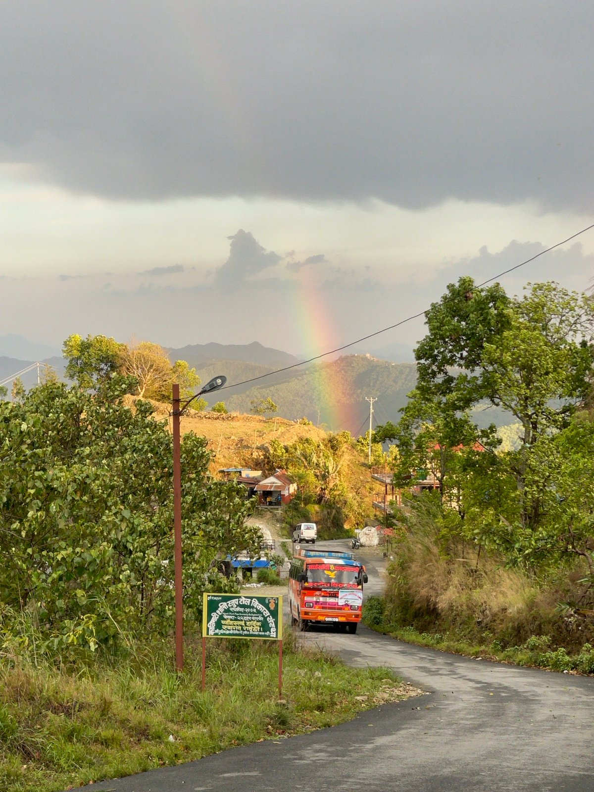 Rainbow arcs over Pokhara mountains amid cloudy Nepal skies