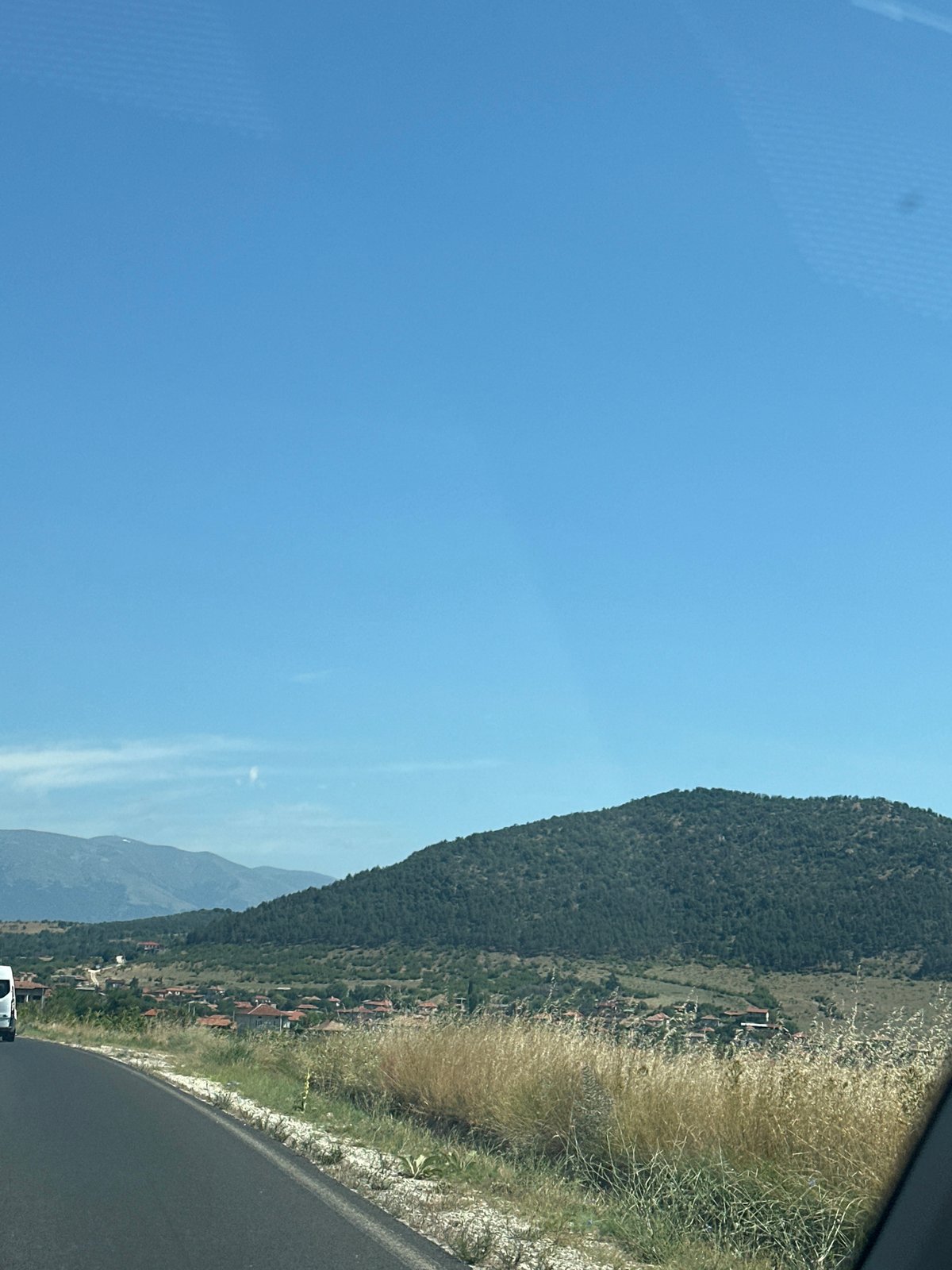 Quiet rural road curves through dry summer landscape in Bulgaria