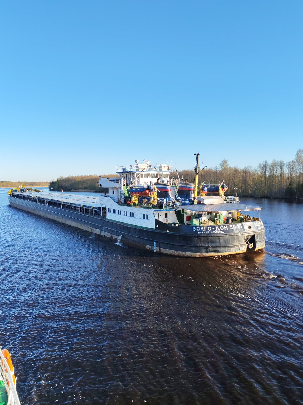 Cargo barge transits Russian waterway near Novokemskii in early morning