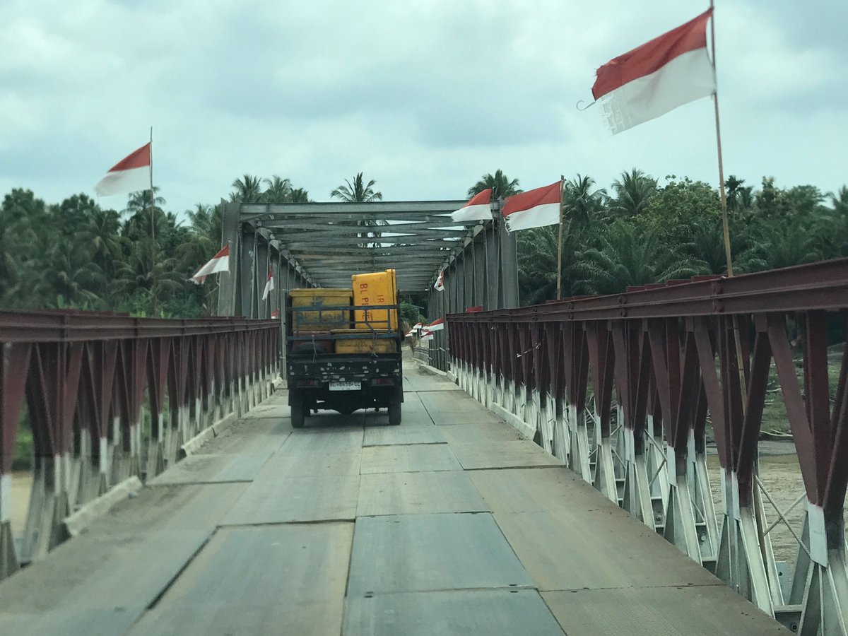 Black pickup with yellow cargo crosses bridge in Indonesia