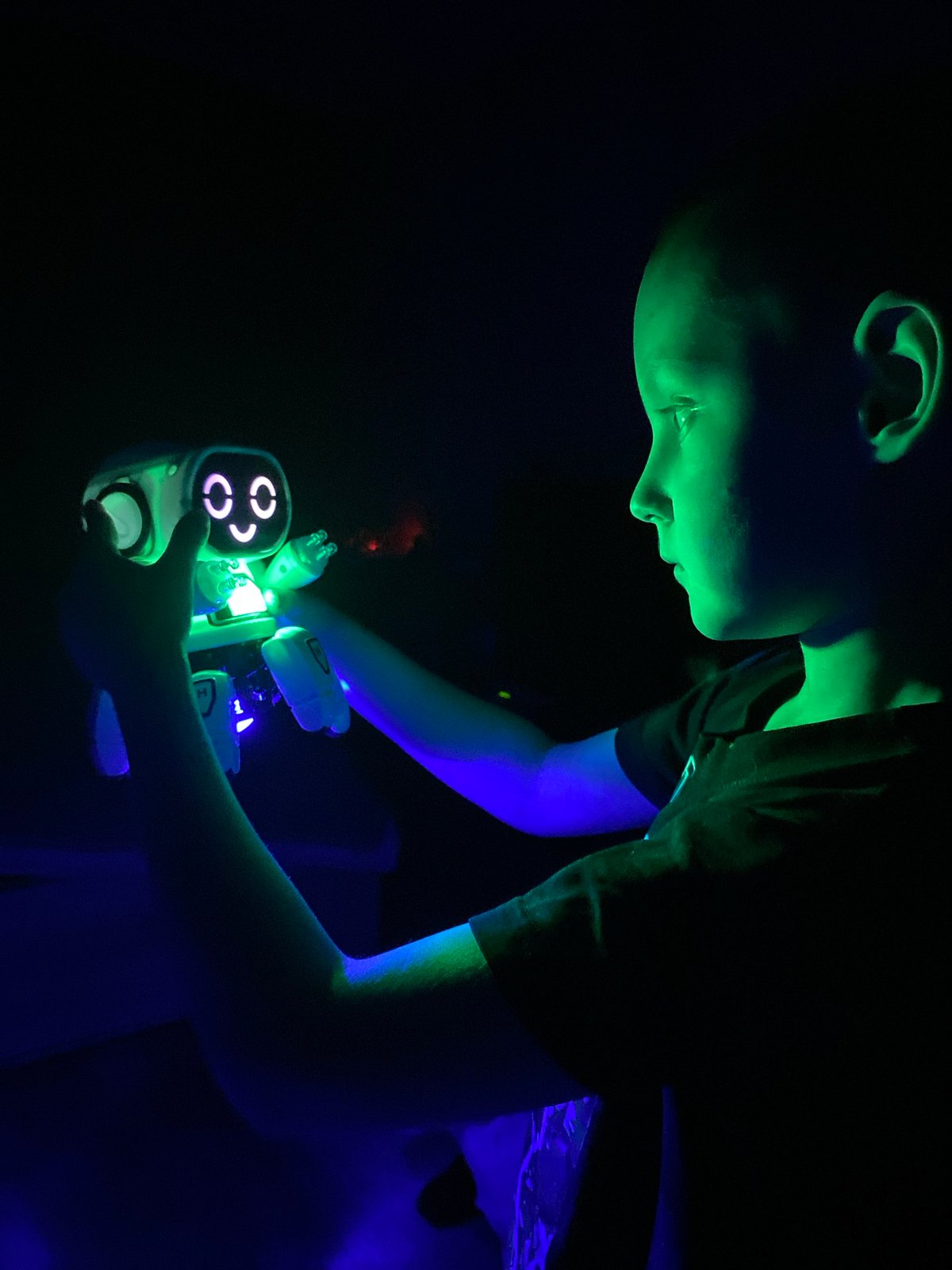 Child plays with glowing RC cars in dimly lit room