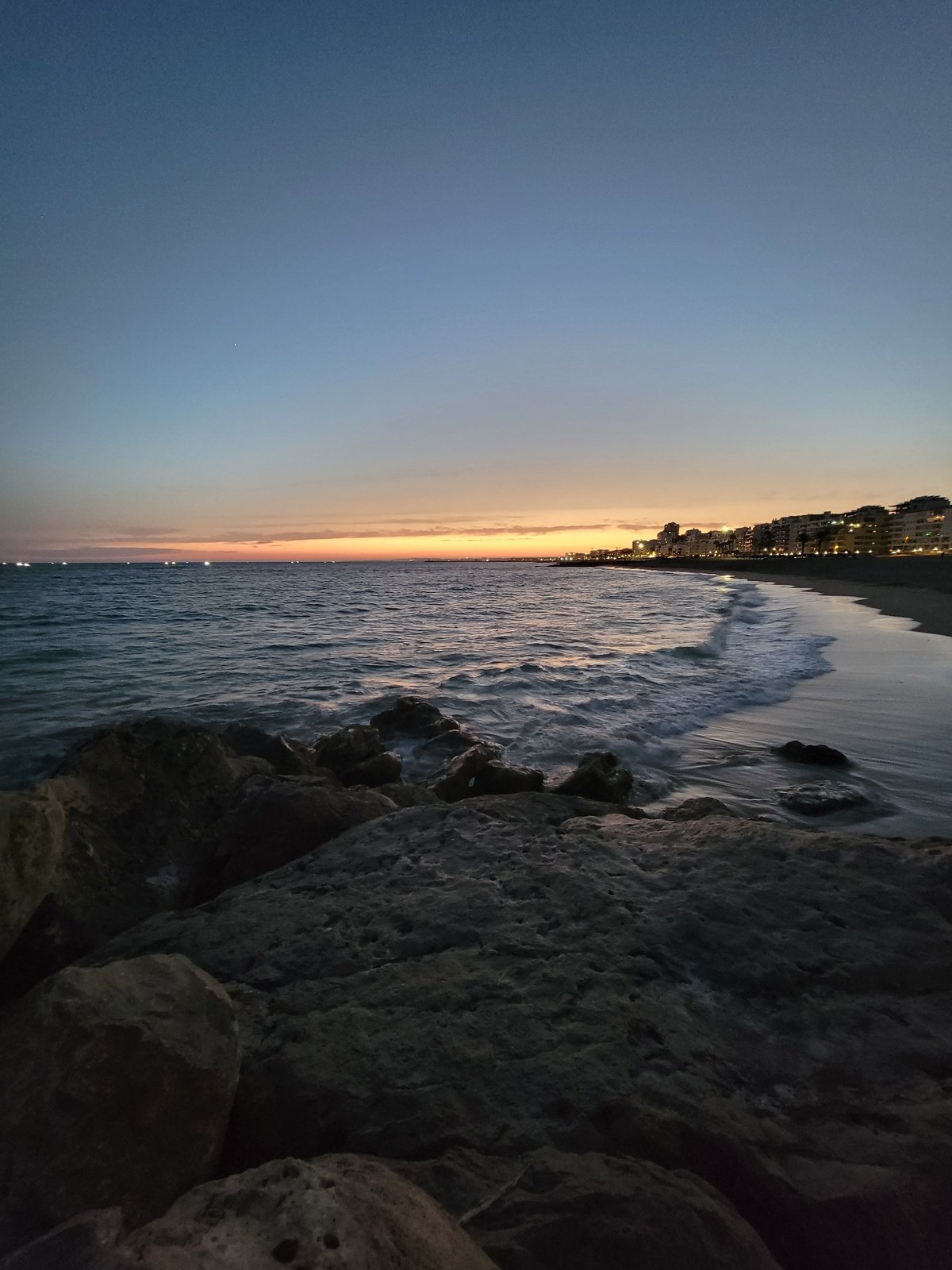 Dusk settles over Quarteira's rocky Atlantic coastline