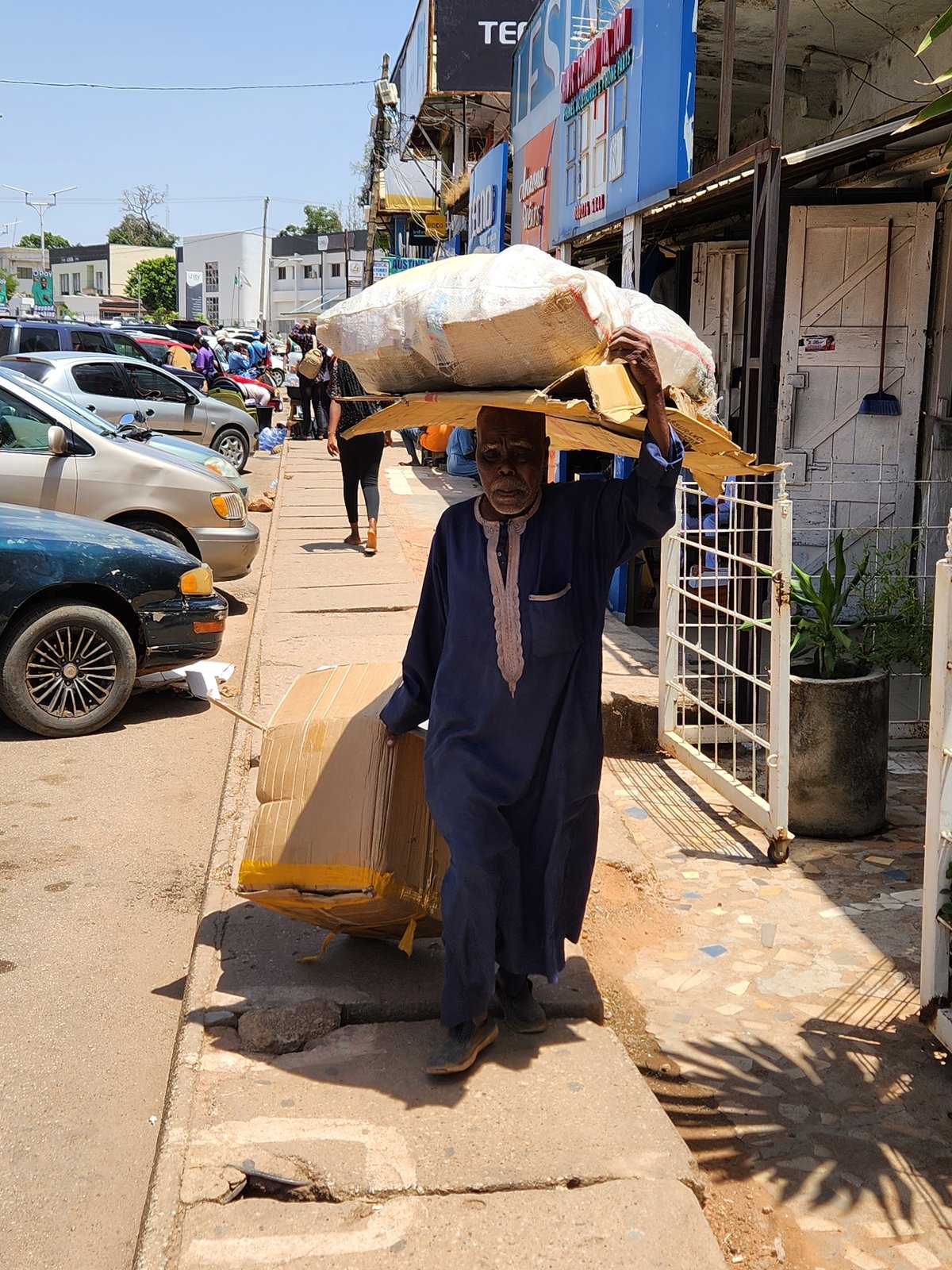 Man carries goods through Jos market area