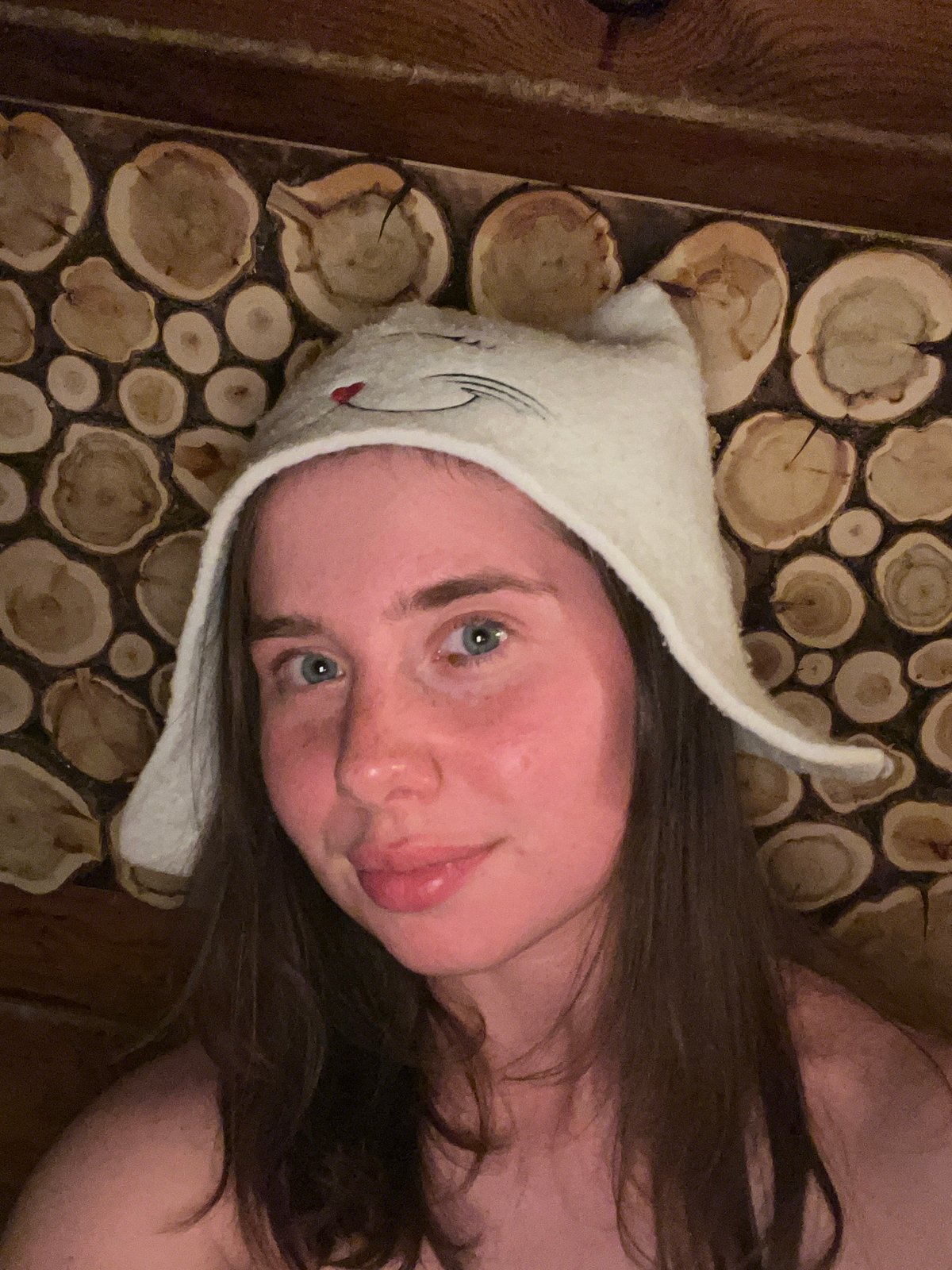 Woman documents sauna session wearing cat hat in Chaikovsky