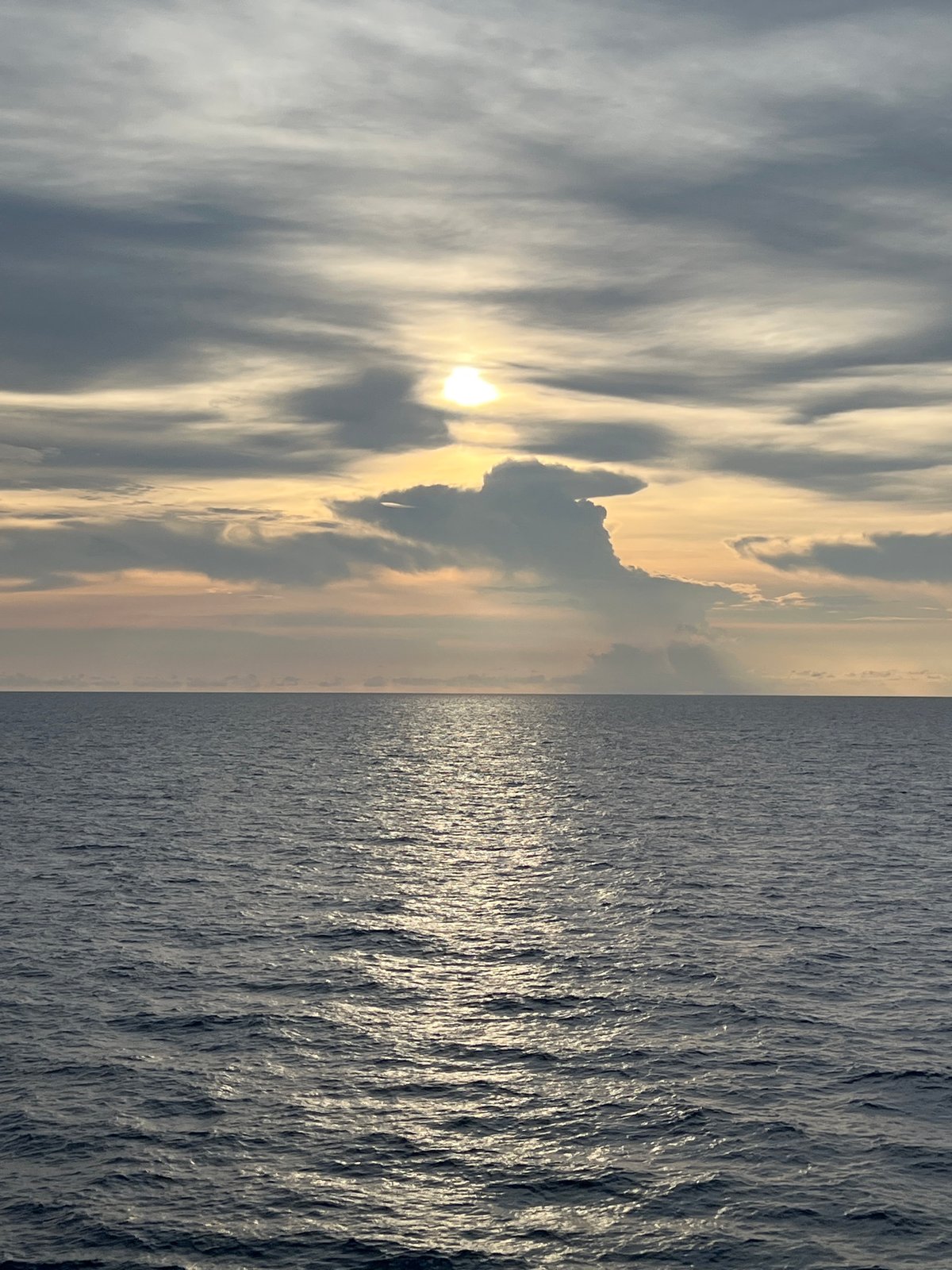 Open ocean views from a ship, sun breaking through clouds