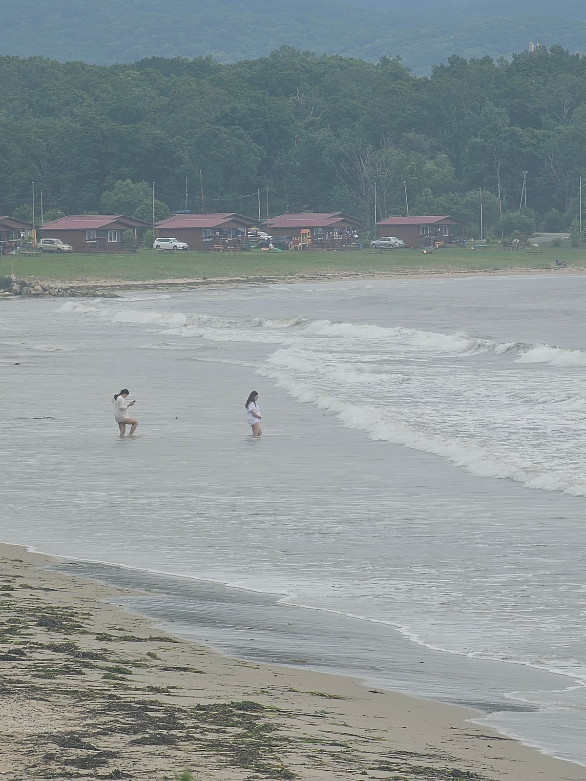 Wading in calm grey water on a cloudy Fokino beach