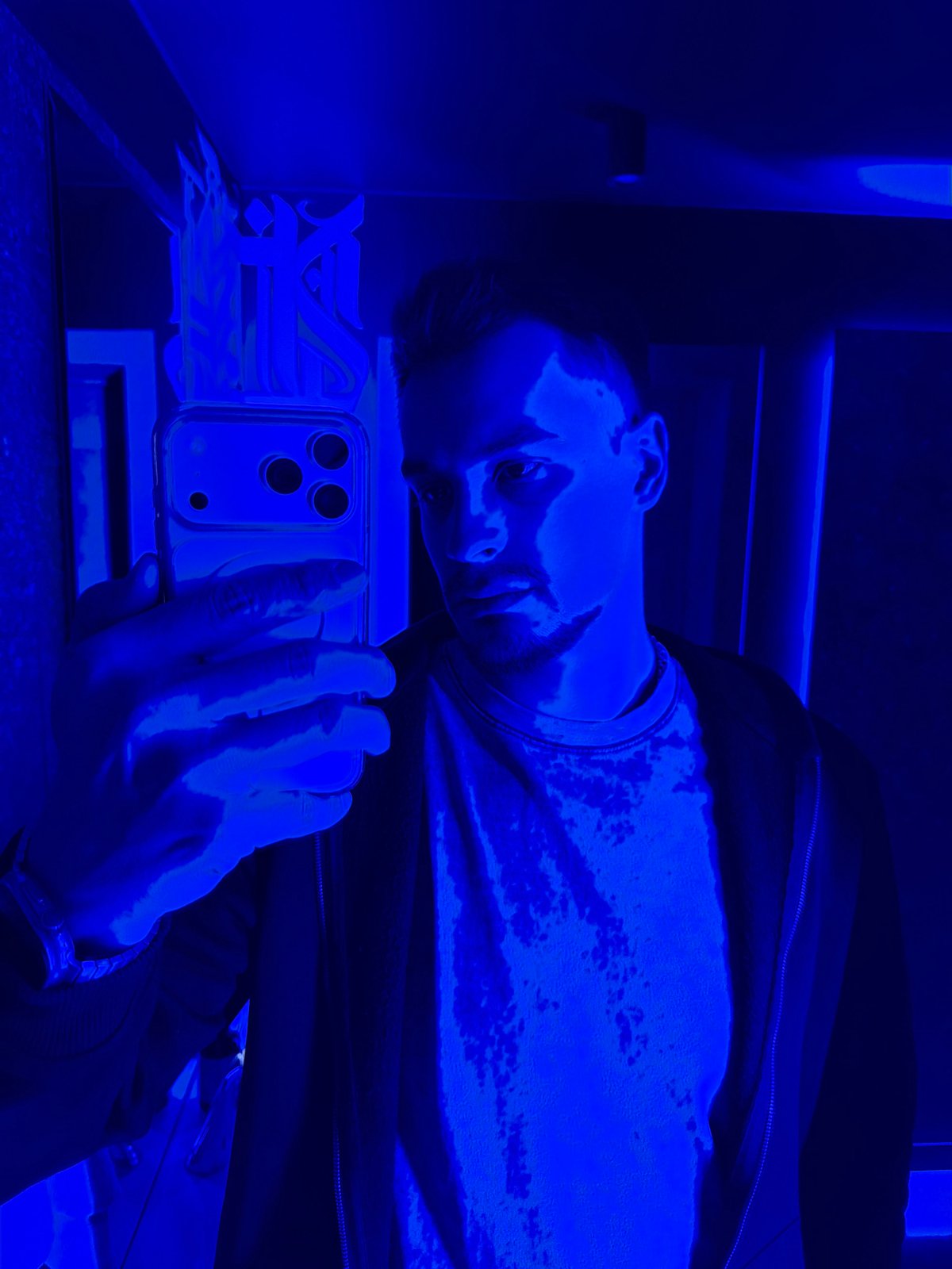 Man photographs with smartphone in dimly lit indoor setting