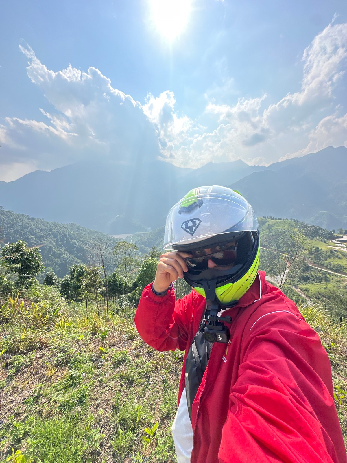 Motorcyclist pauses in Vietnam's terraced mountain landscape