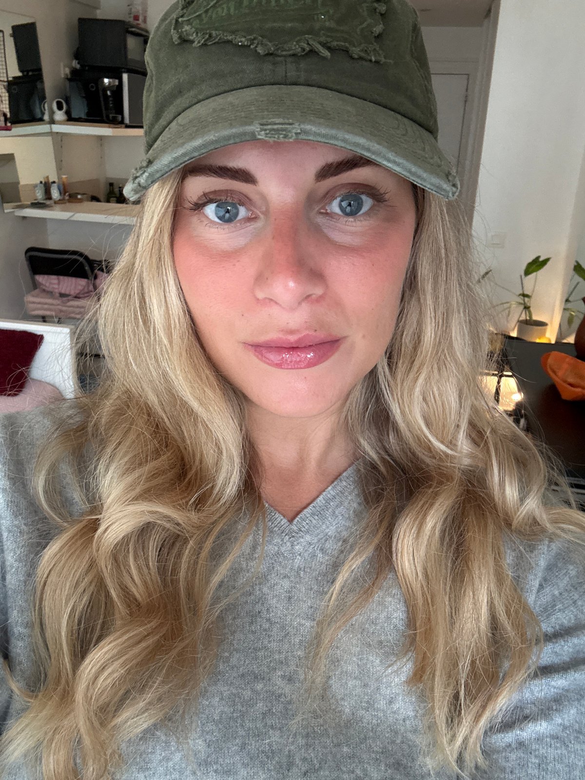 Woman takes selfies in Paris apartment wearing green cap