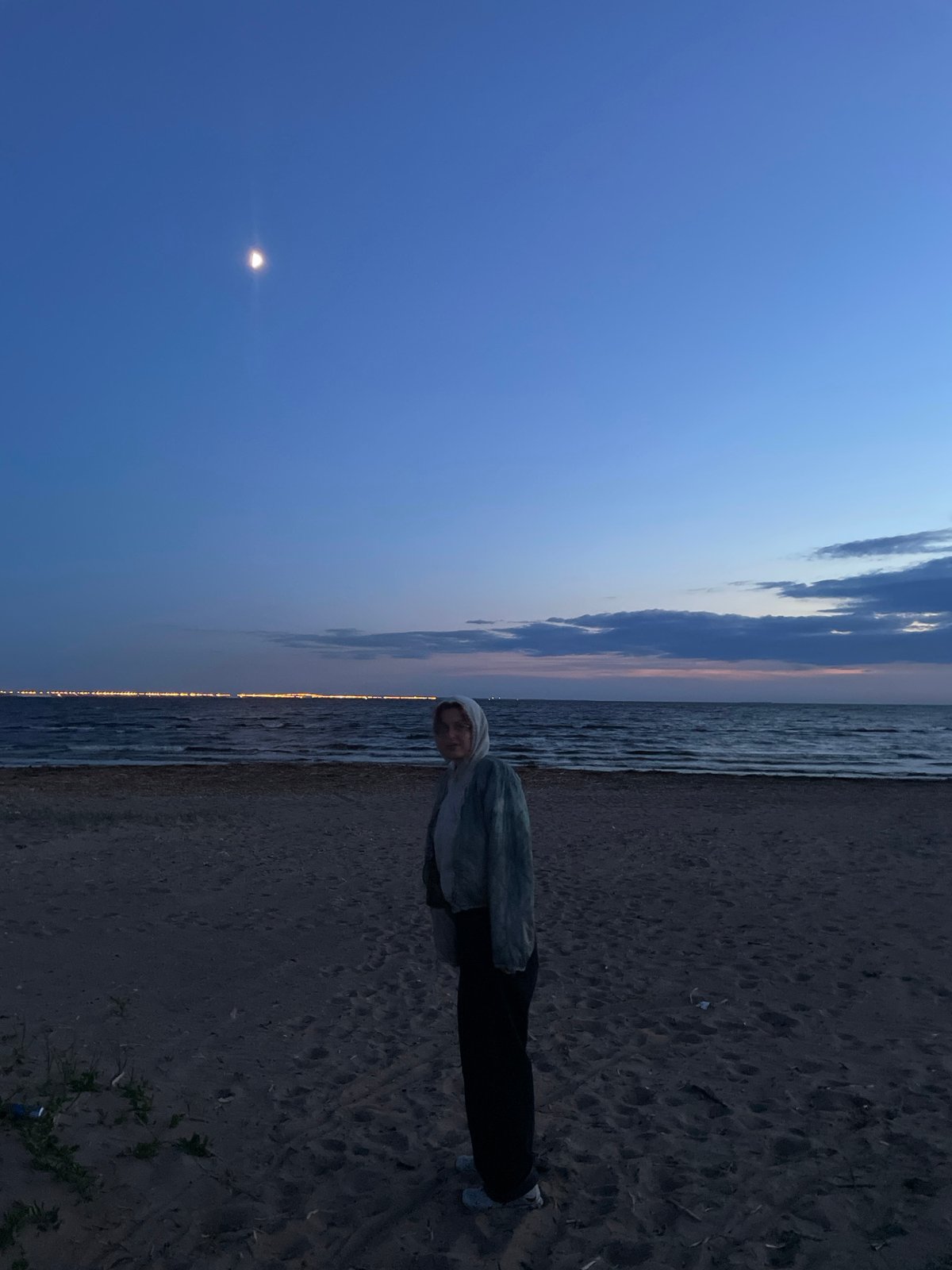 Solitary figure stands on Sestroretsk beach at twilight