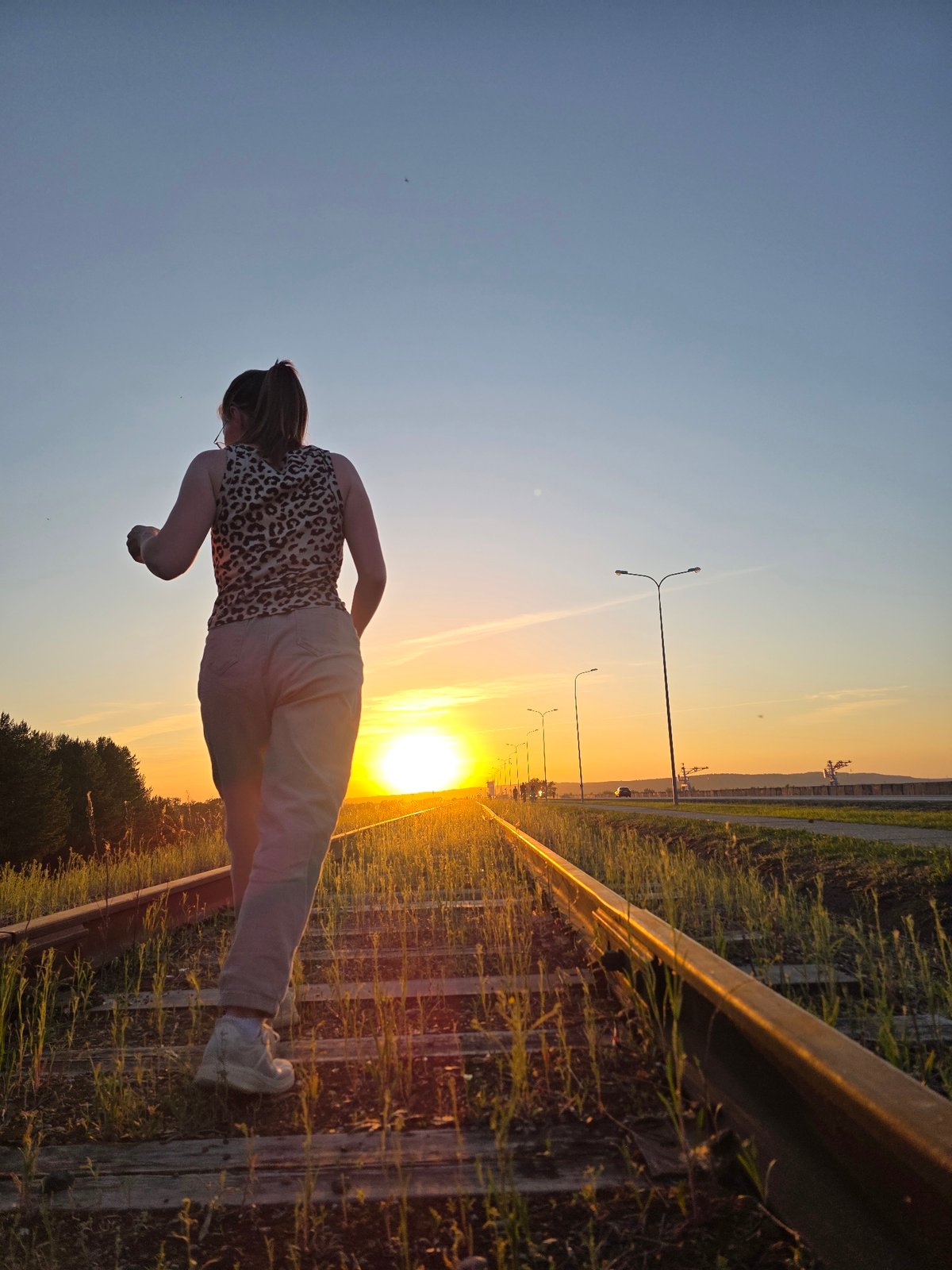 Woman poses on railway tracks during sunset in Chaikovsky