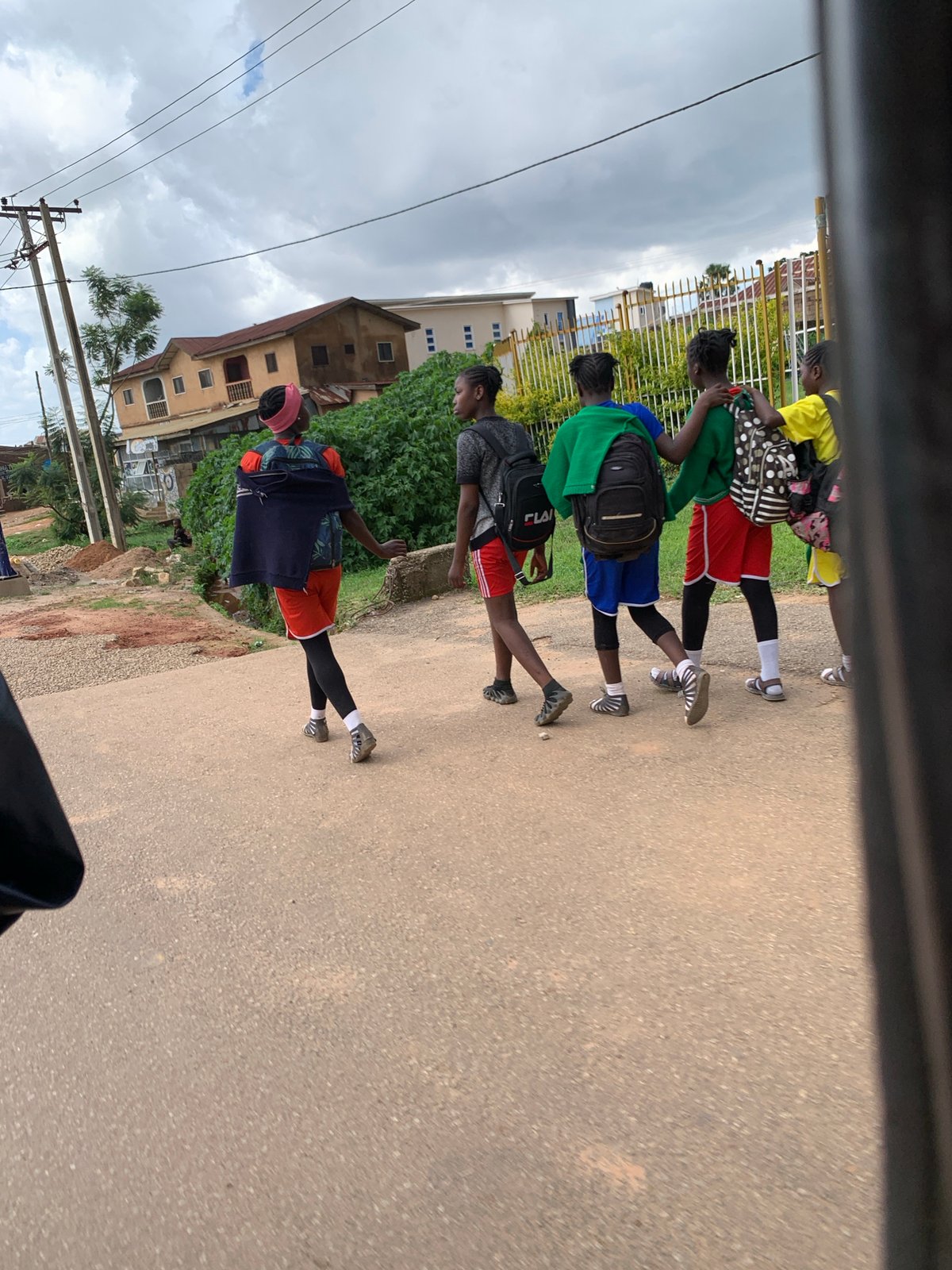 Students moving through Jos streets on a cloudy afternoon