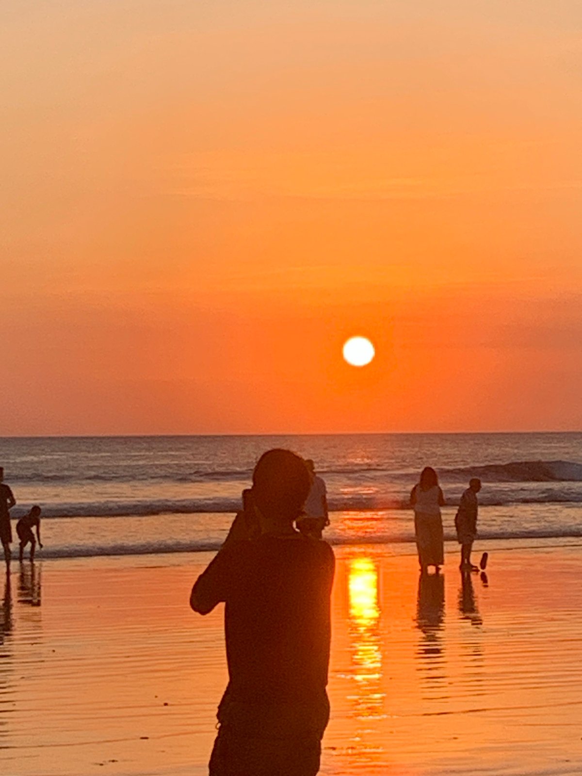 Kuta Beach fills up at sunset, orange sky and all