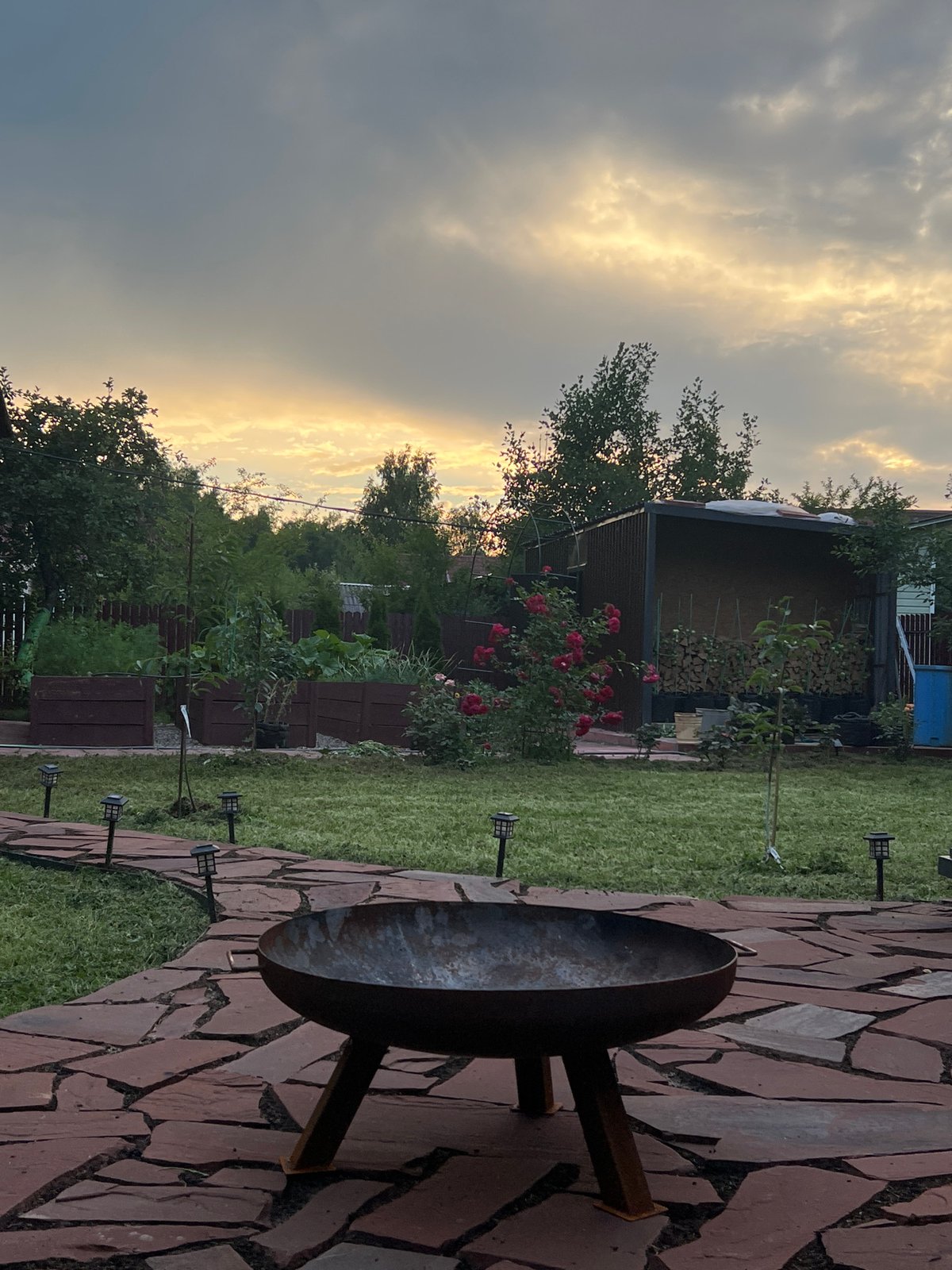 Dusk settles over a rustic backyard with a fire pit in Luch