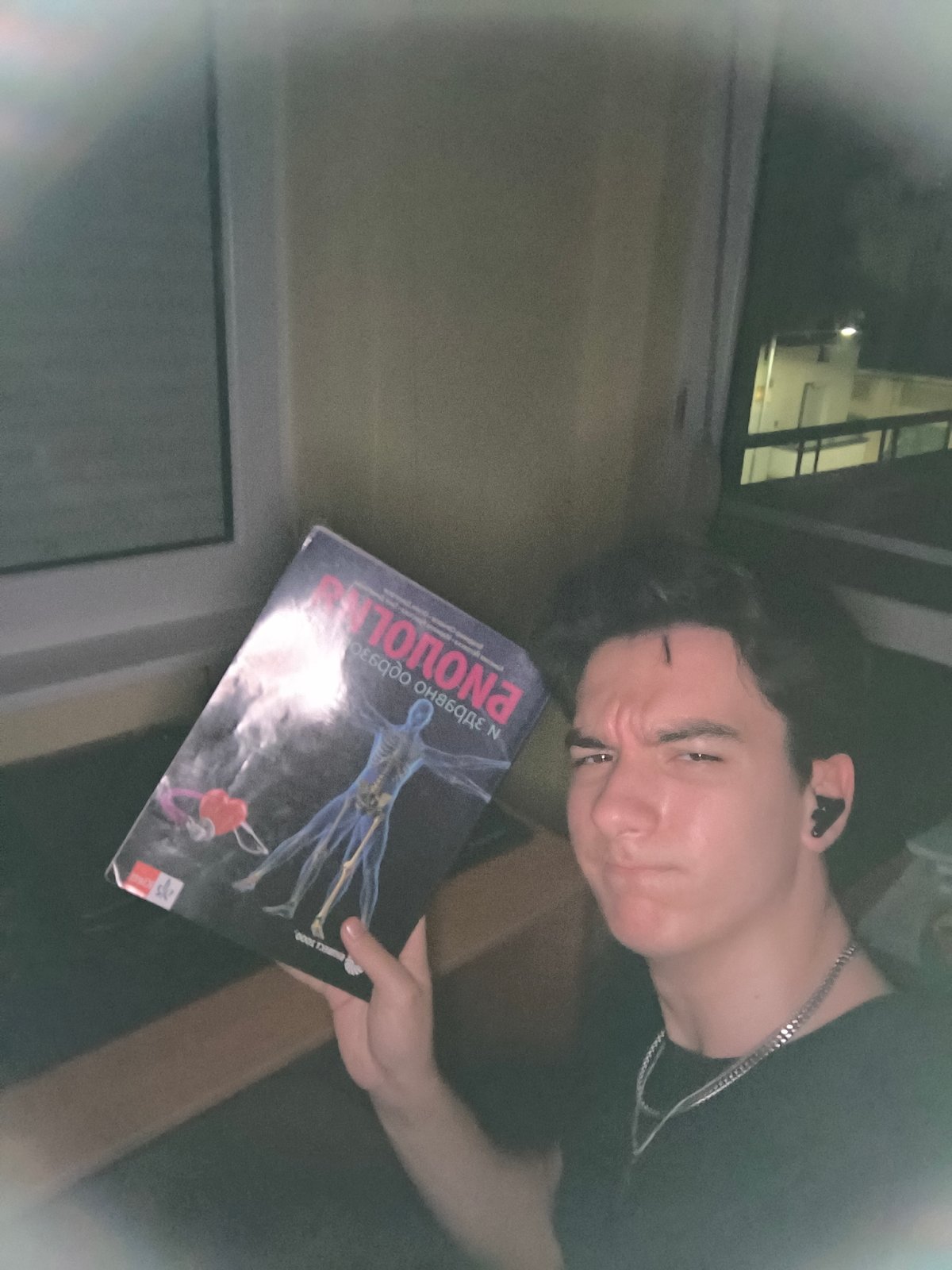 Young man reading encyclopedia, resting in Pleven apartment evening